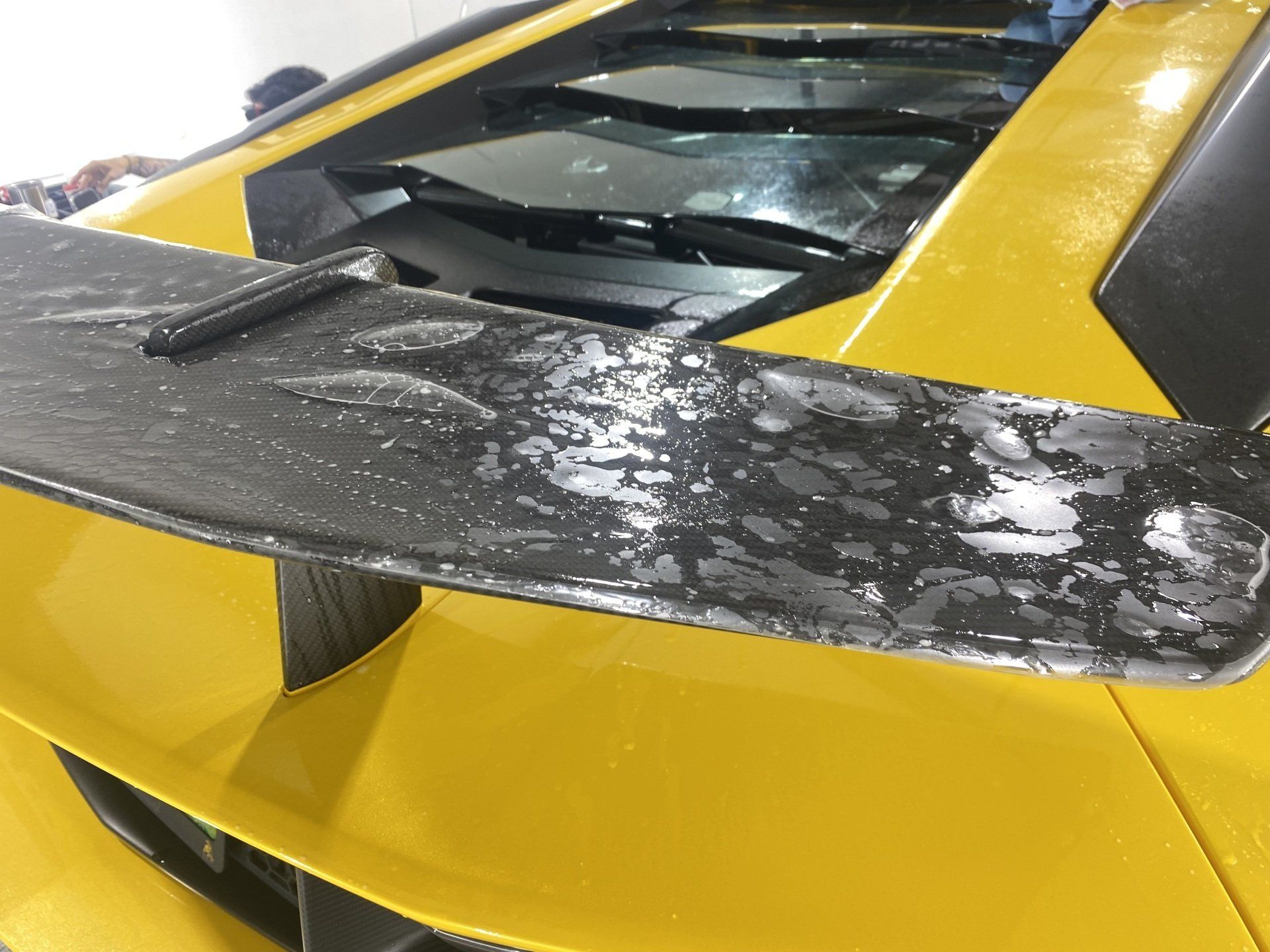 A close up of a yellow sports car with a black wing