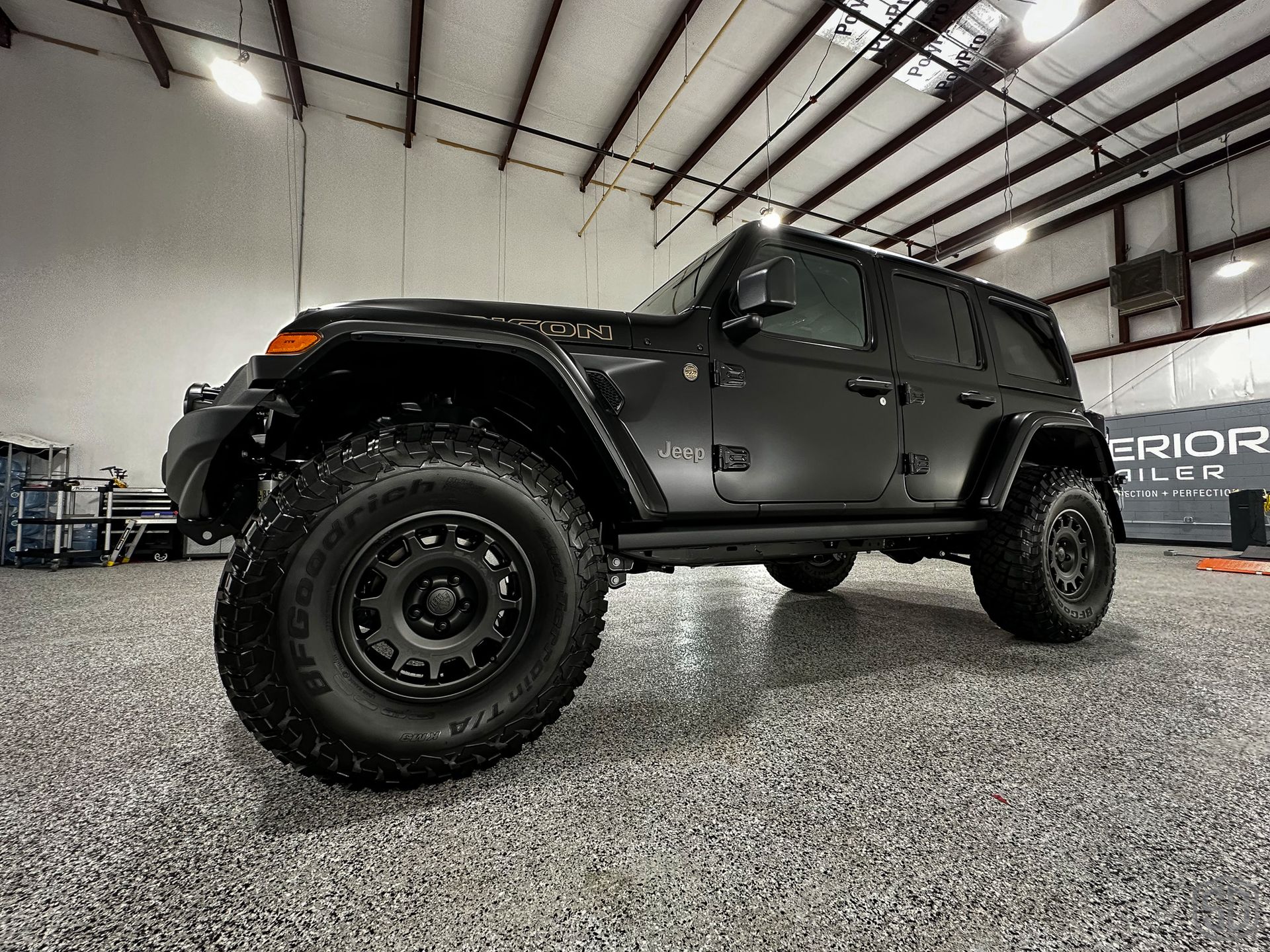 A black jeep wrangler is parked in a garage.