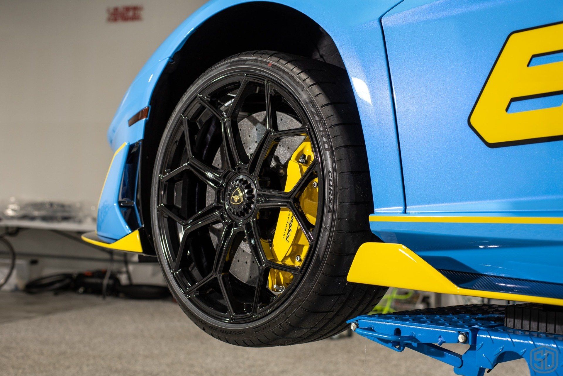 A blue and yellow sports car is sitting on a lift.