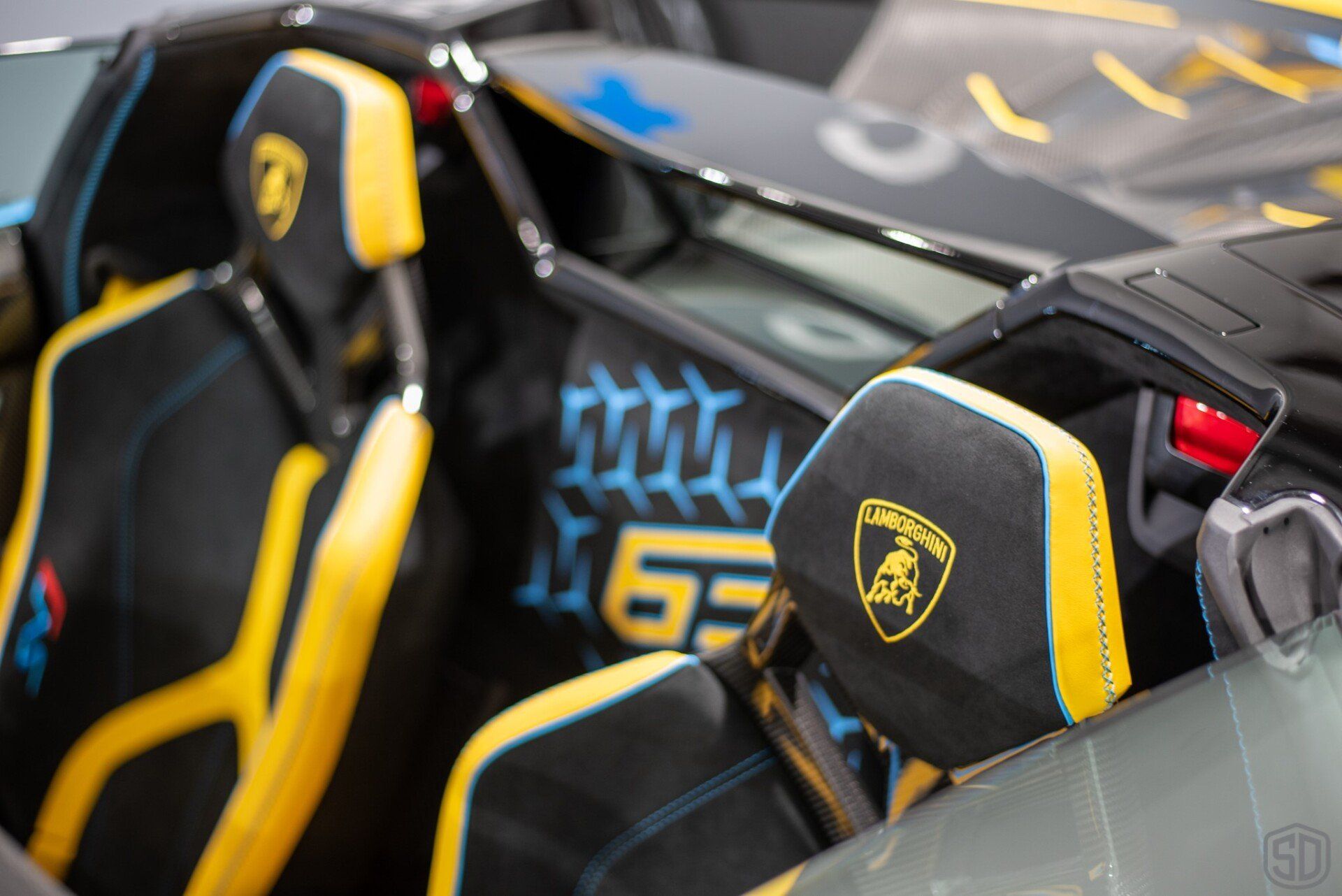A close up of the interior of a lamborghini with yellow and black seats.