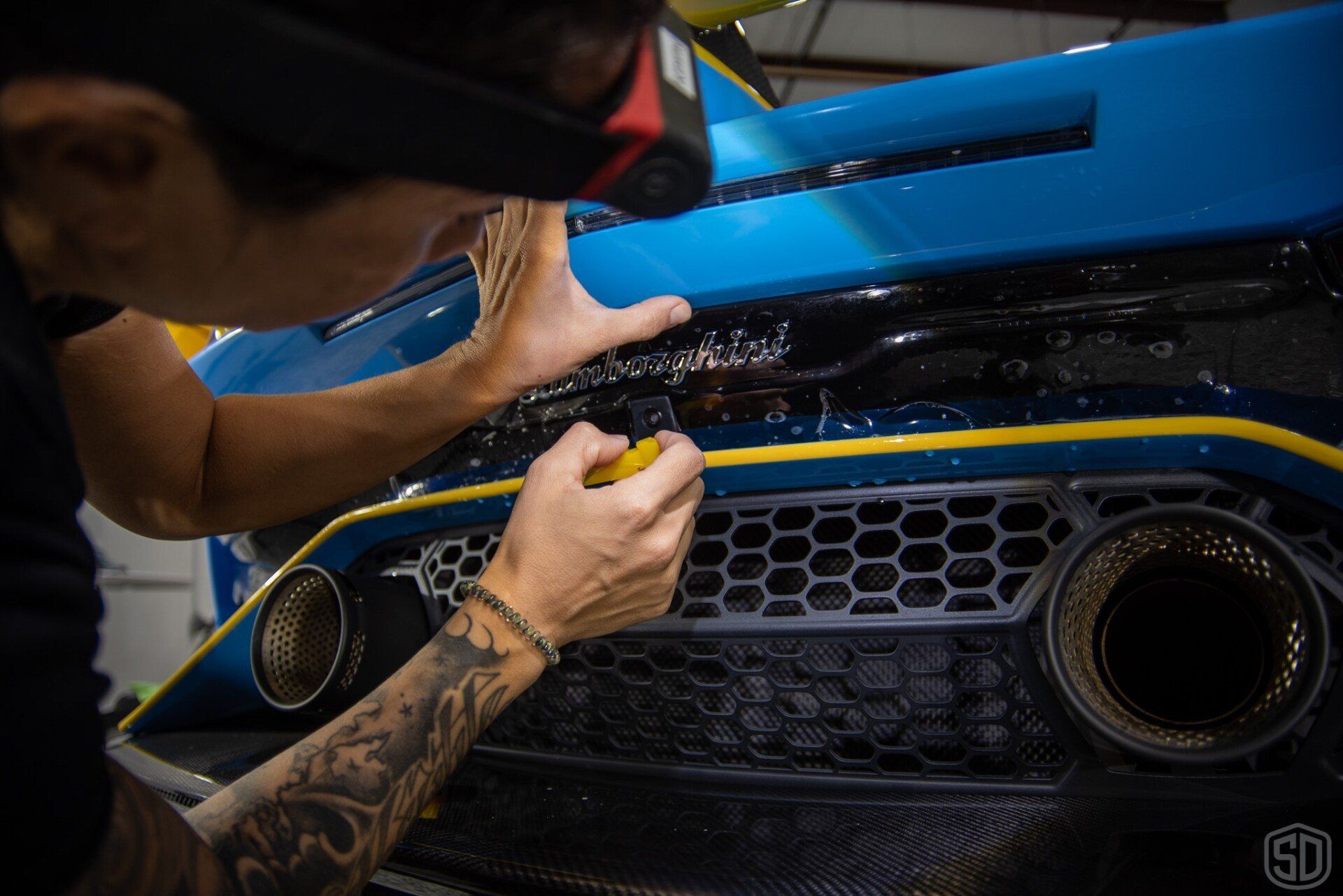 A man is working on the front of a blue car.