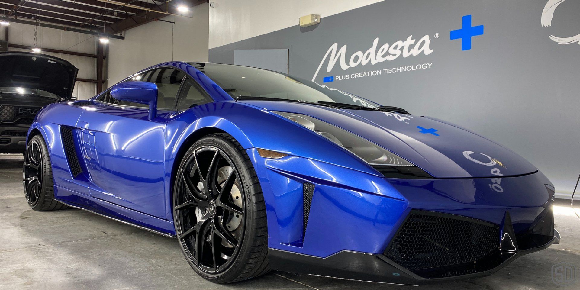 A blue lamborghini gallardo is parked in a garage.