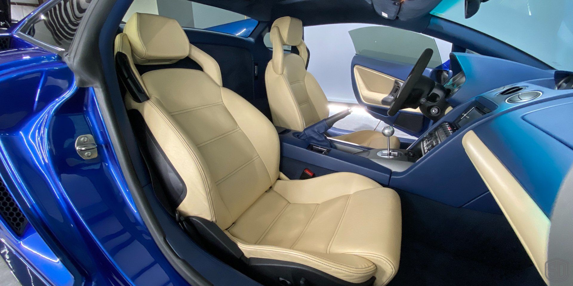 The interior of a blue sports car with tan leather seats.
