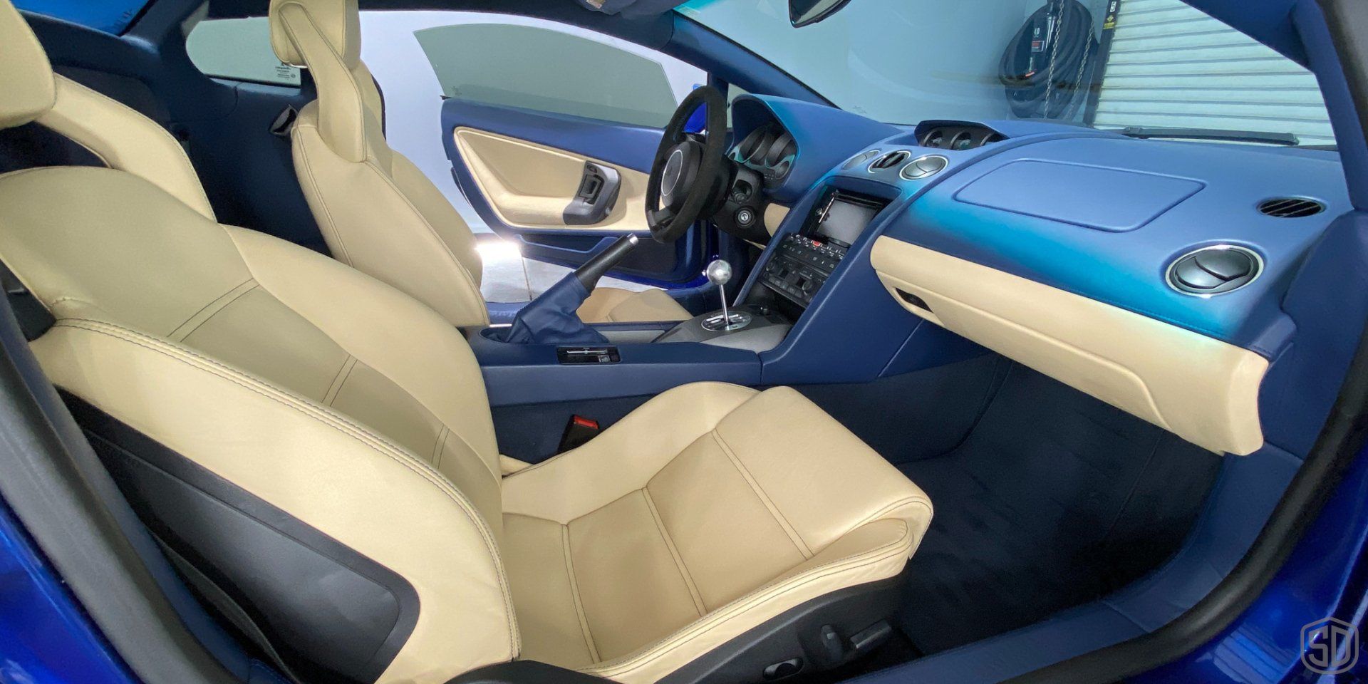 The interior of a blue sports car with tan leather seats