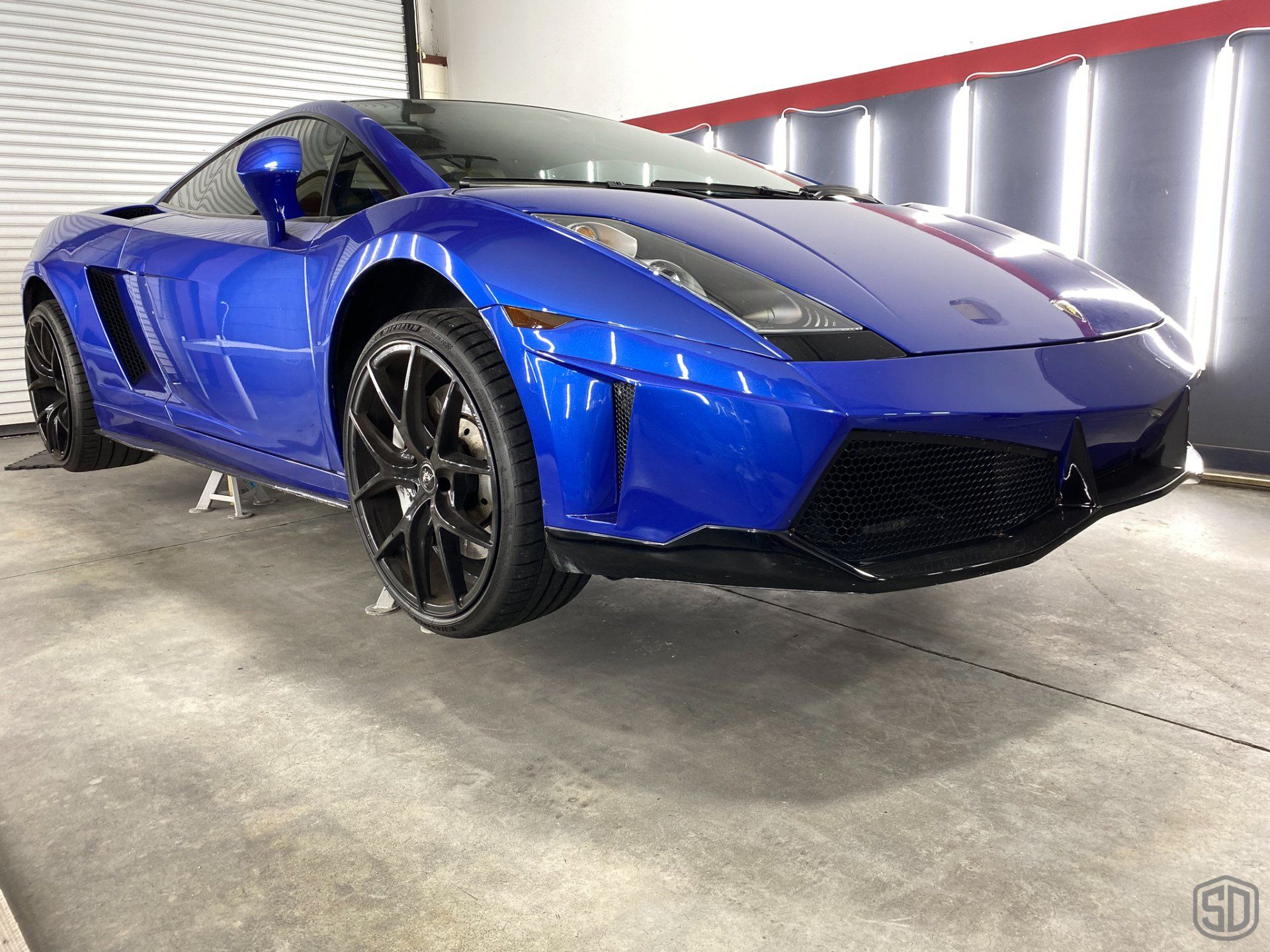A blue lamborghini gallardo is parked in a garage.