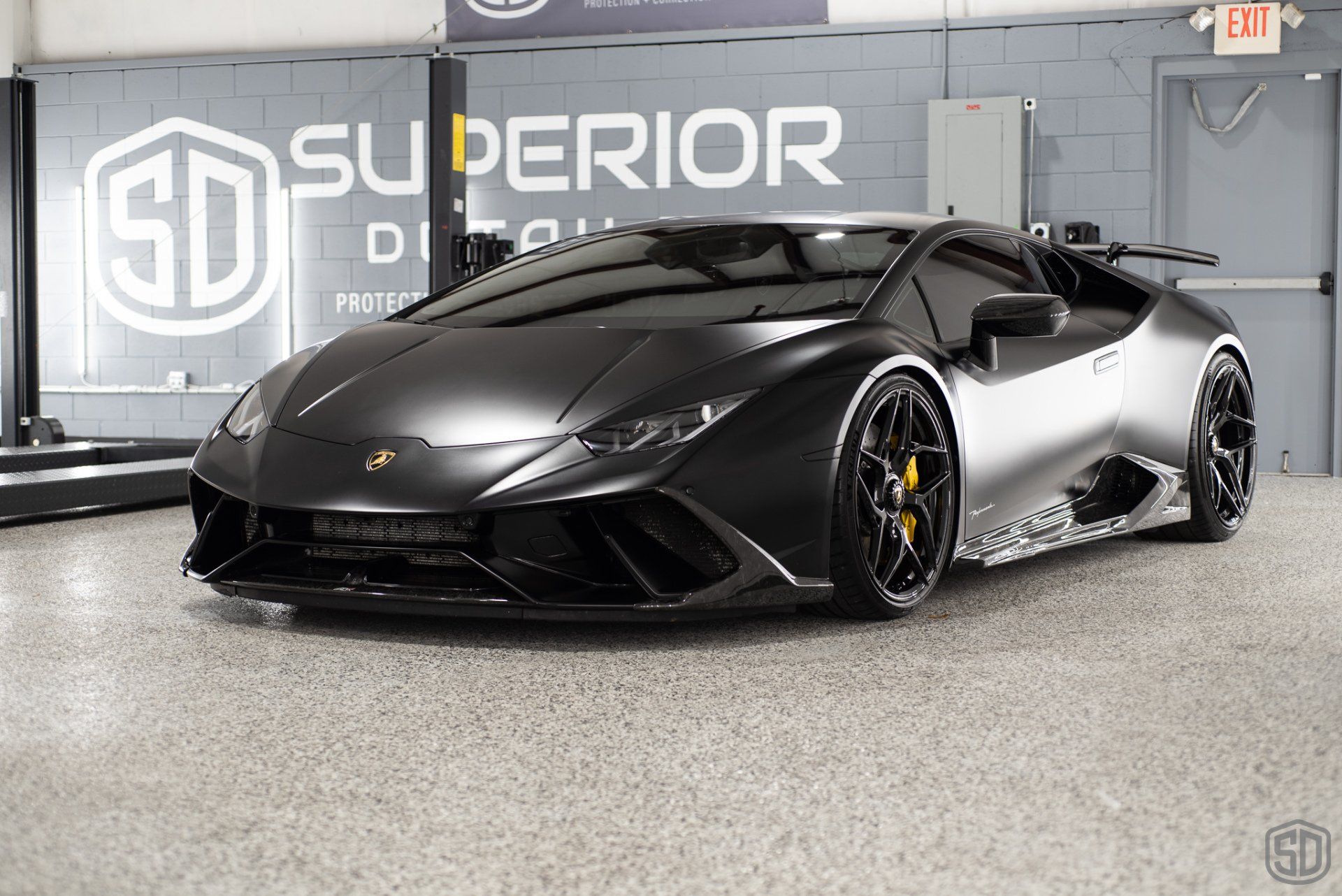 A black lamborghini huracan is parked in a garage.