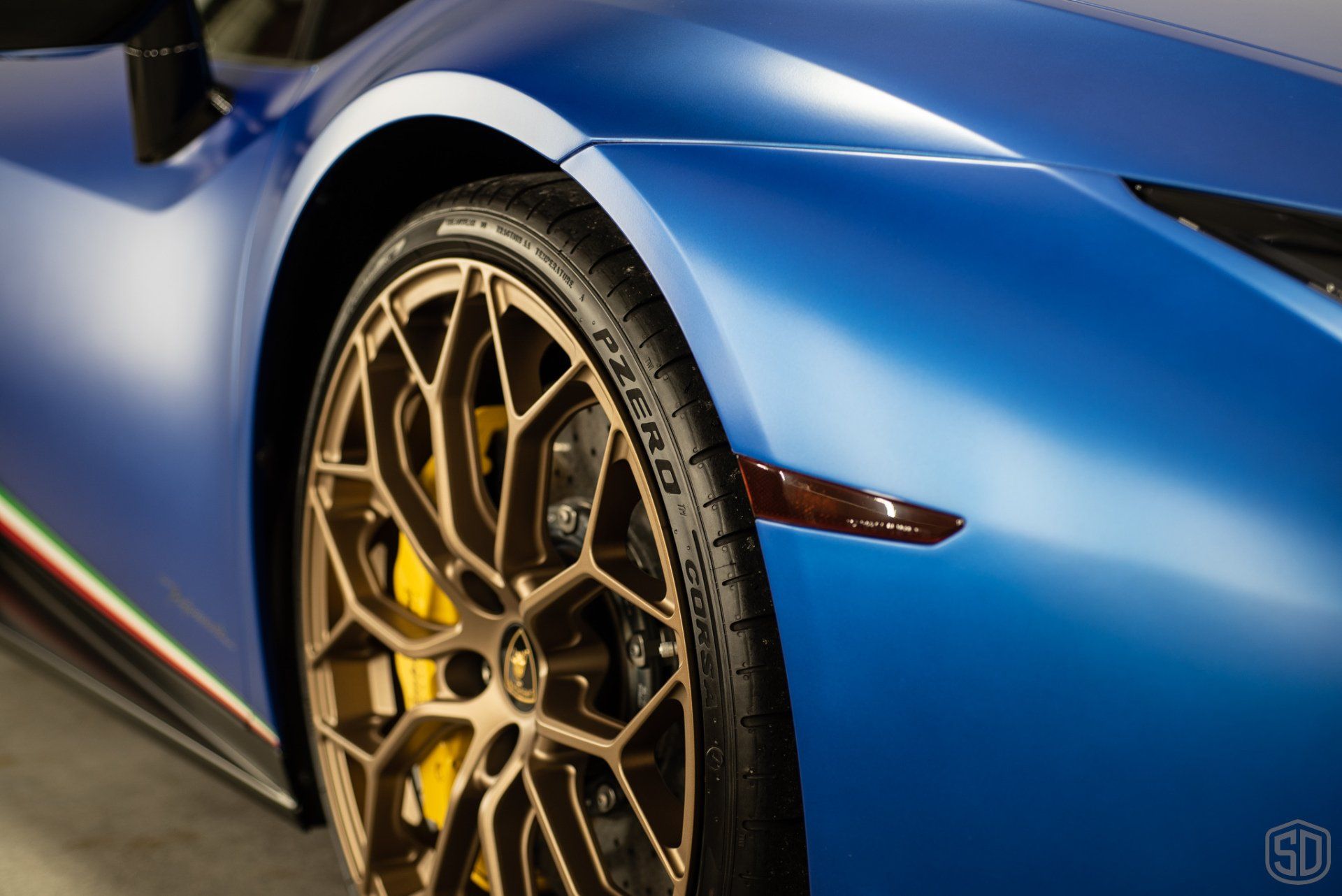 A close up of a blue sports car with gold wheels