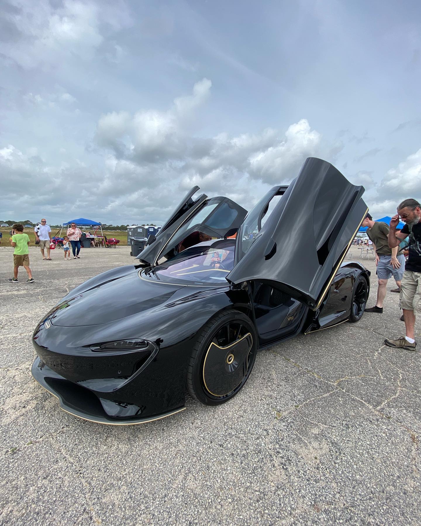 A black sports car with its doors open is parked on the side of the road.