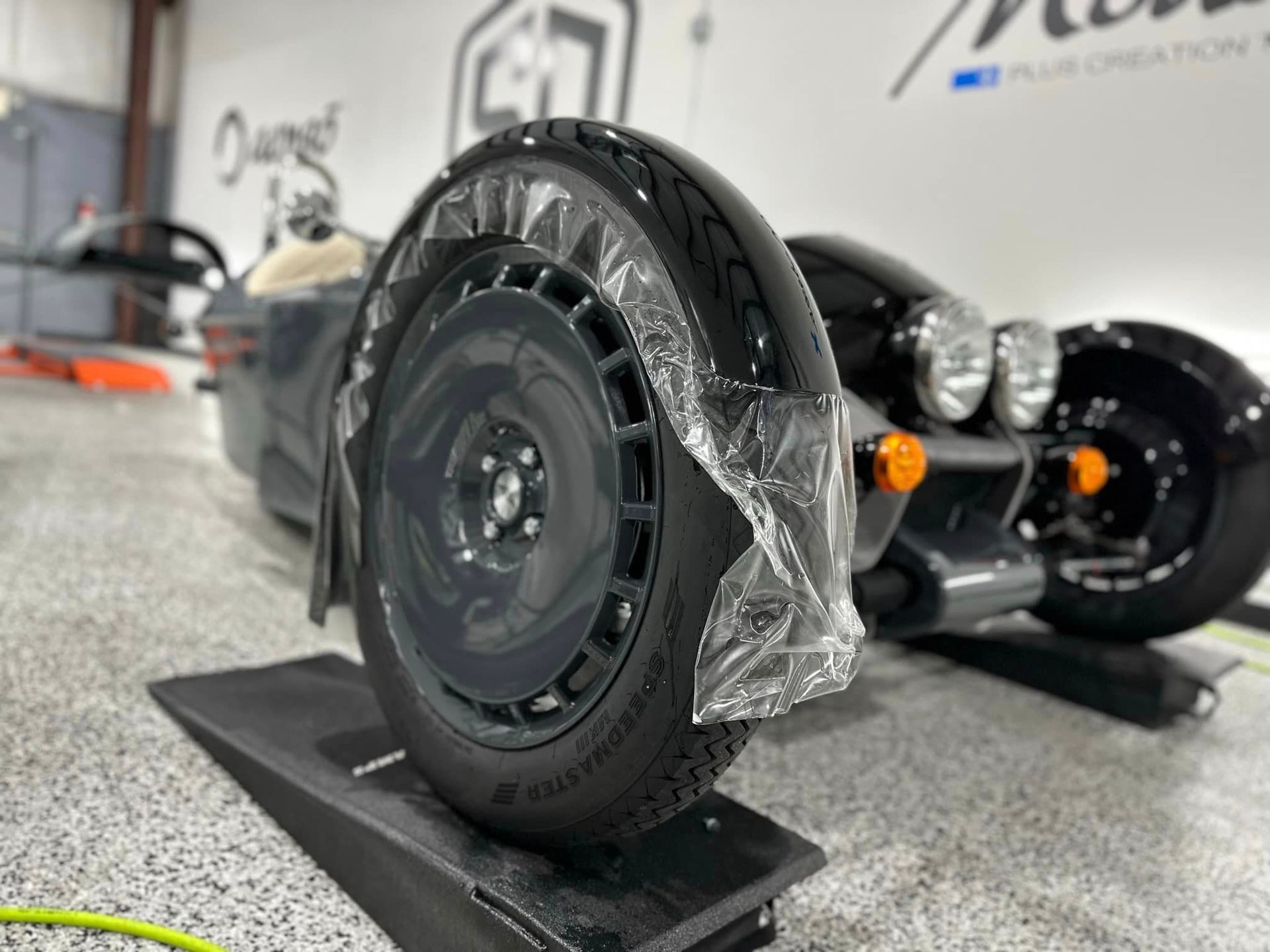 A car wheel is wrapped in plastic and sitting on a ramp.
