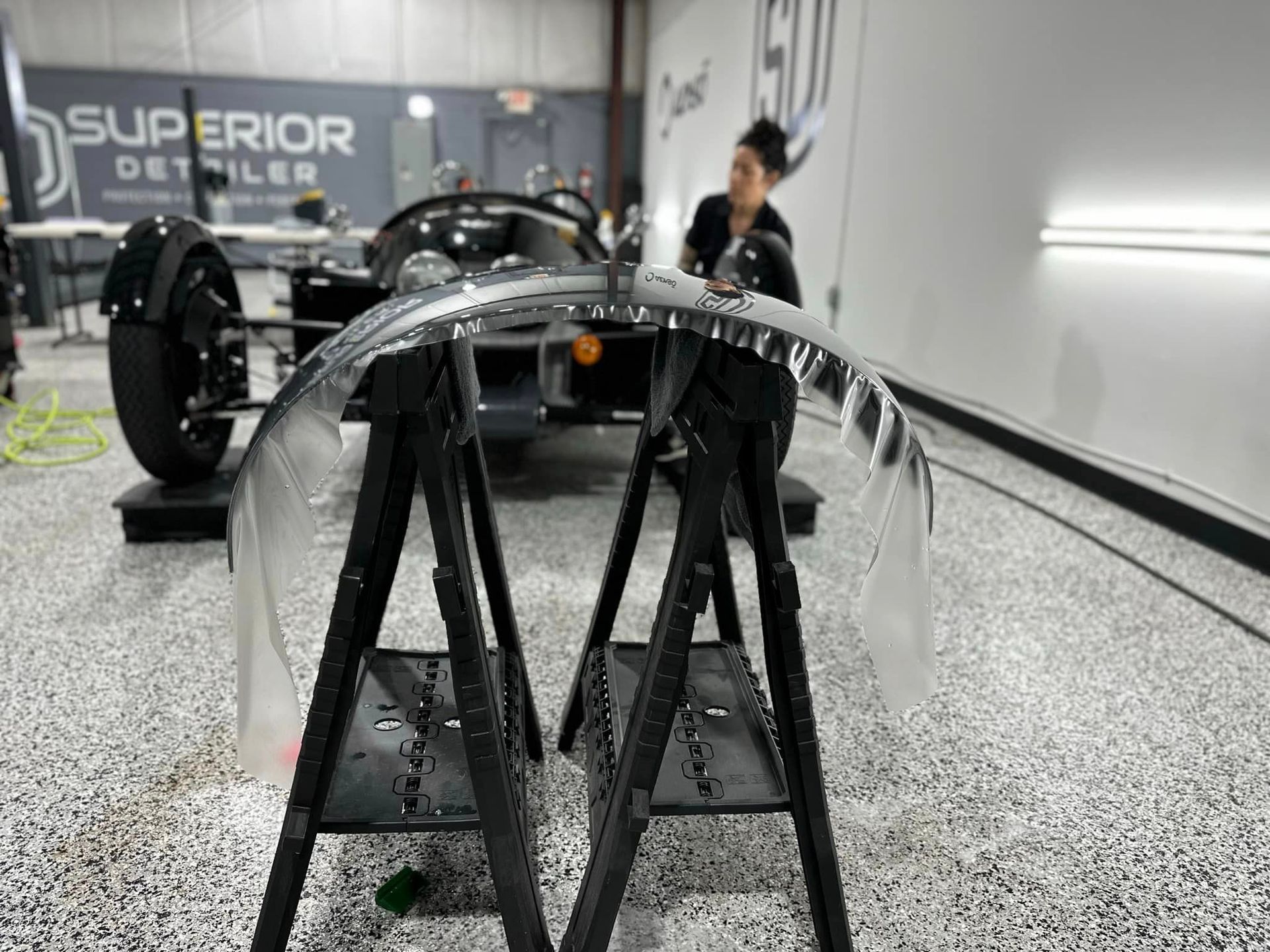 A woman is working on a car in a garage.