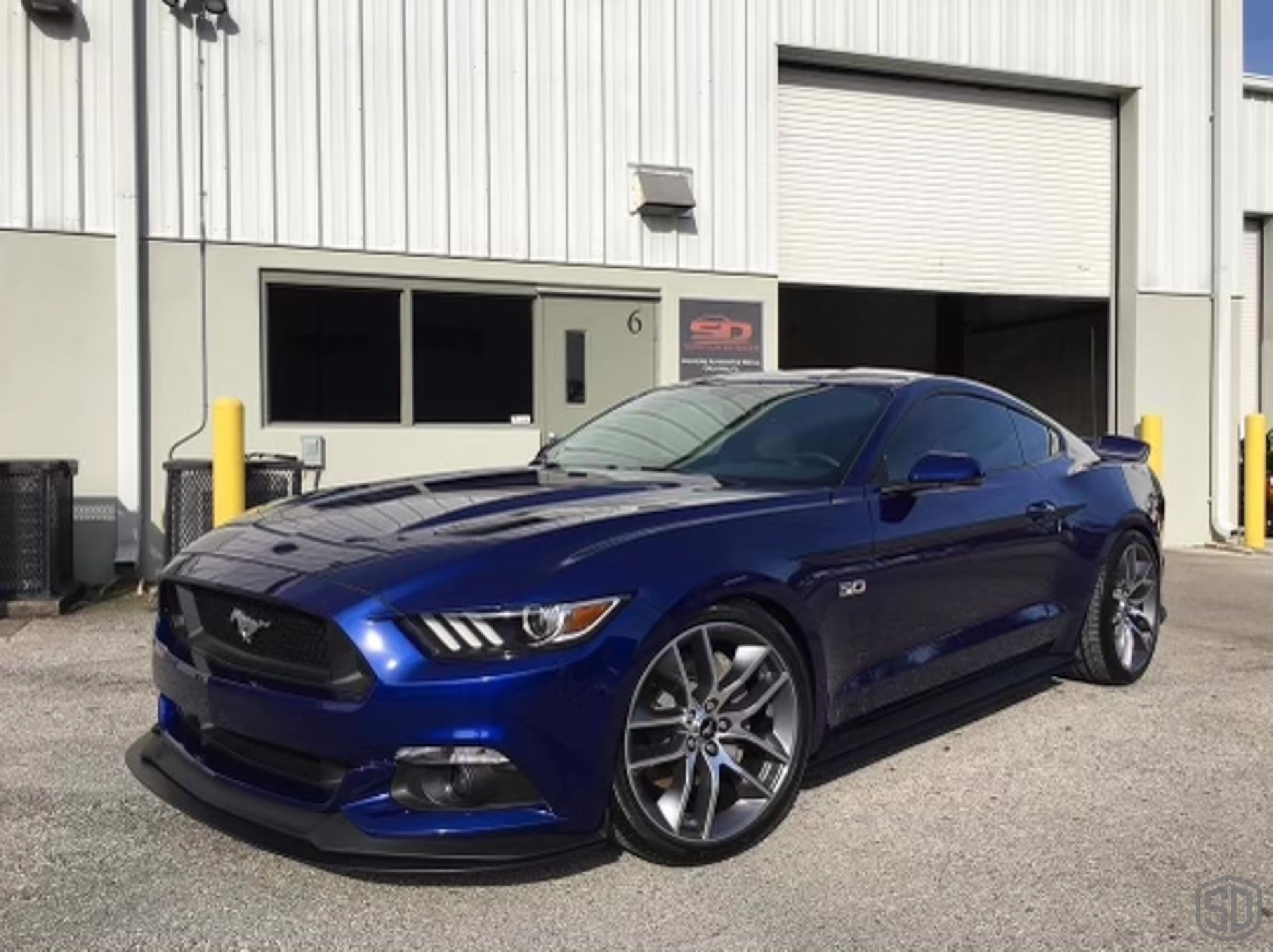 A blue ford mustang is parked in front of a building.