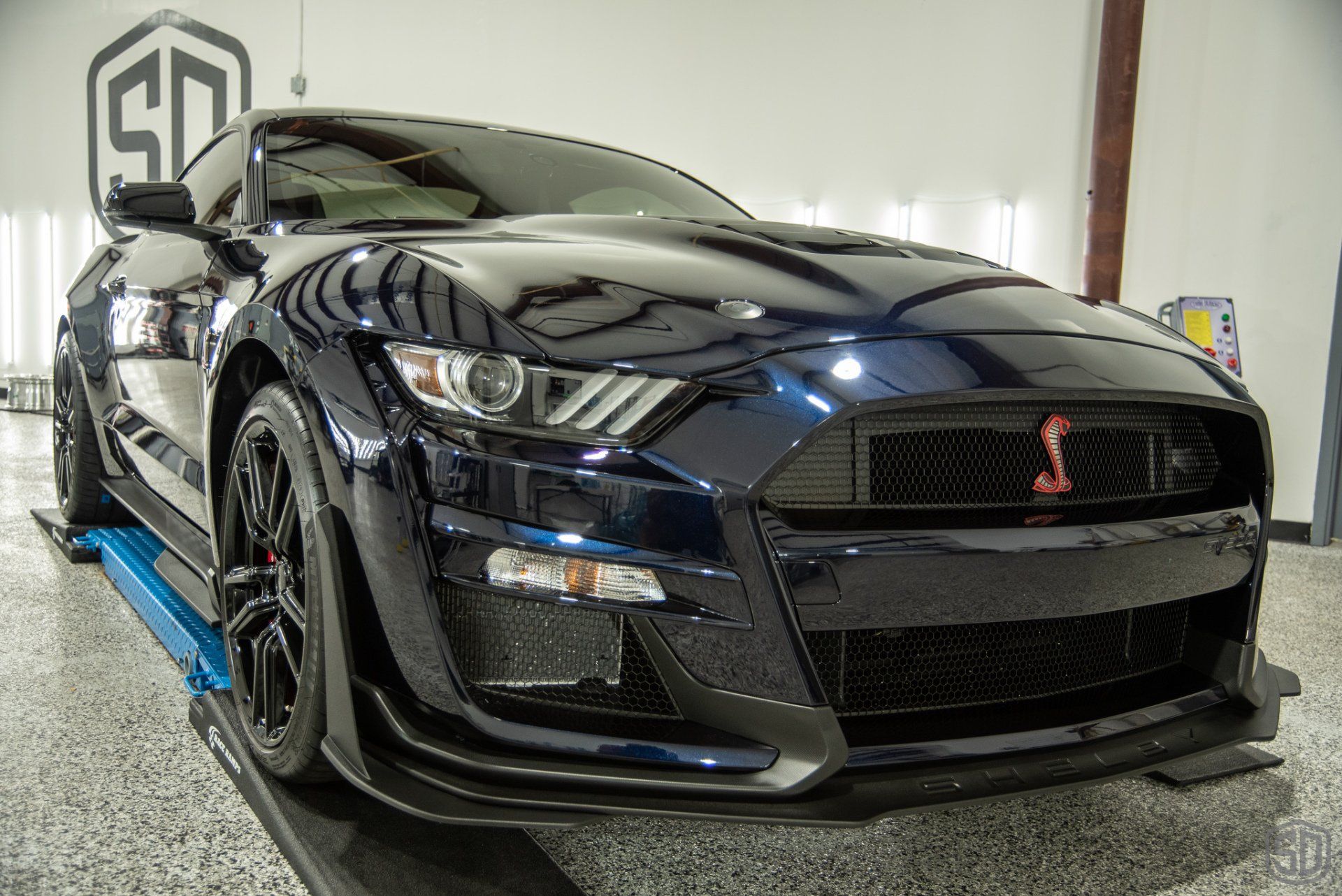 A black ford mustang is parked on a lift in a garage.