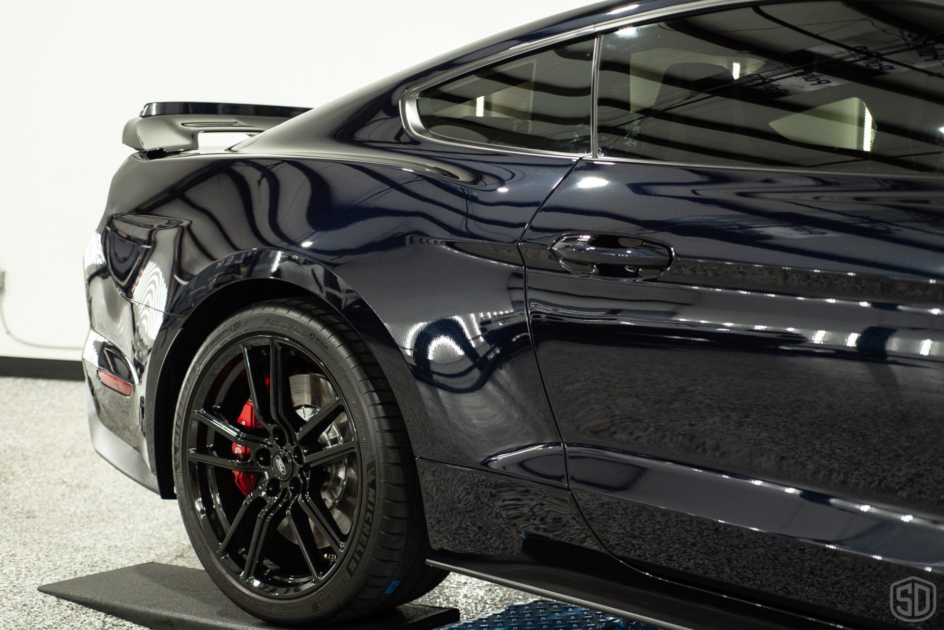 A black ford mustang is parked in a garage.