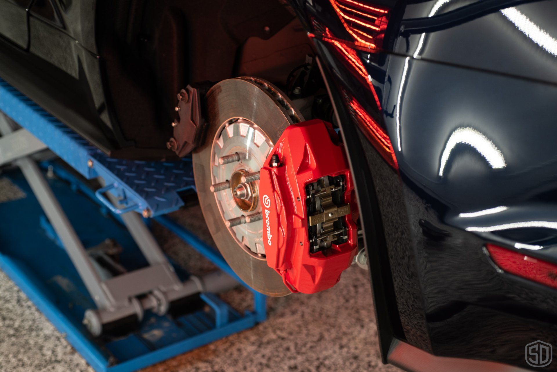 A close up of a car with a red brembo brake caliper.