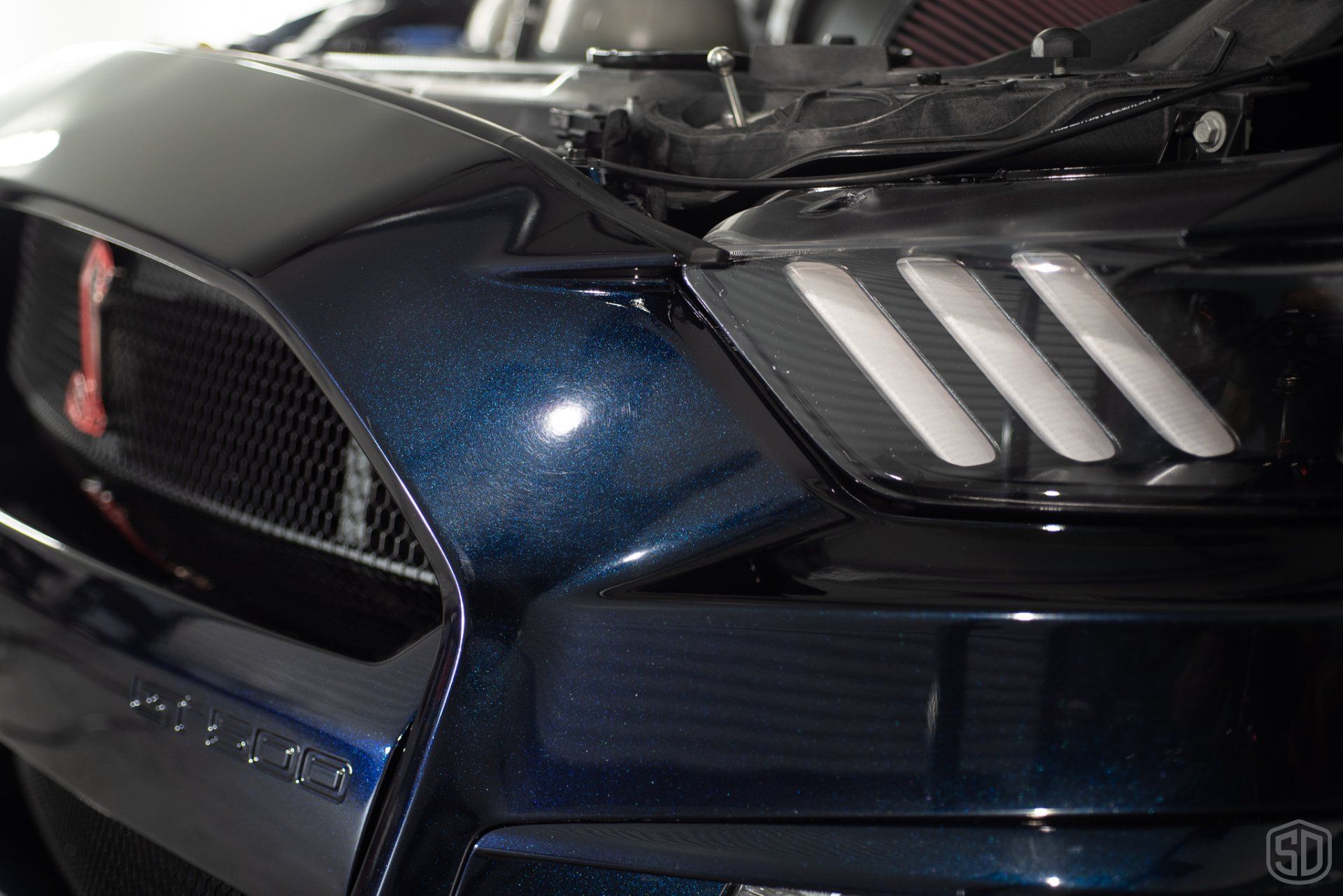 A close up of the front of a ford mustang with the hood open.