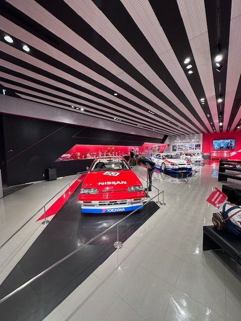 A red nissan car is on display in a museum