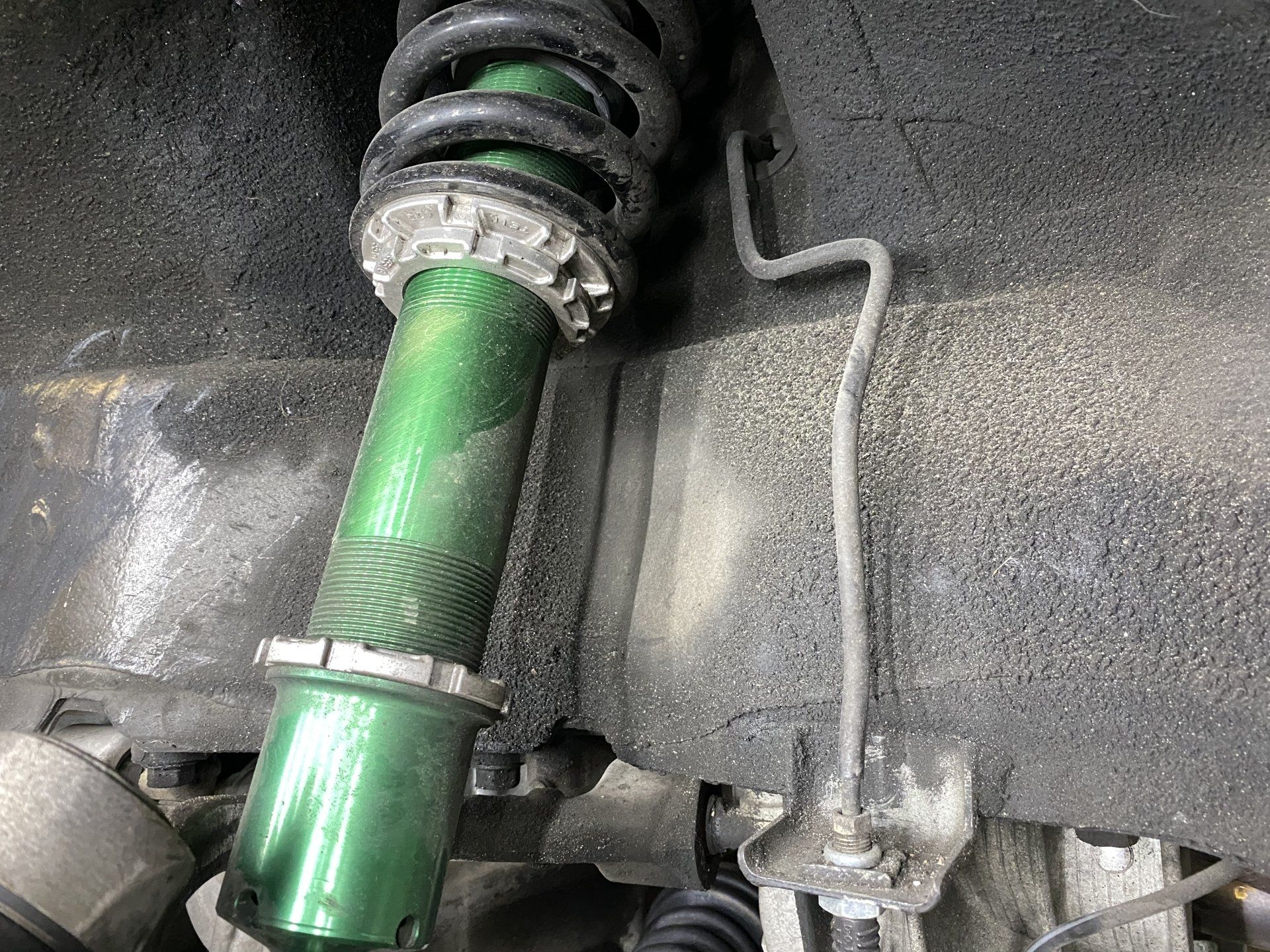 A close up of a green shock absorber on a car.