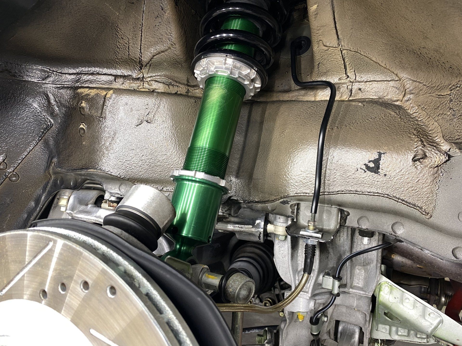 A green shock absorber is sitting next to a brake disc in a car.
