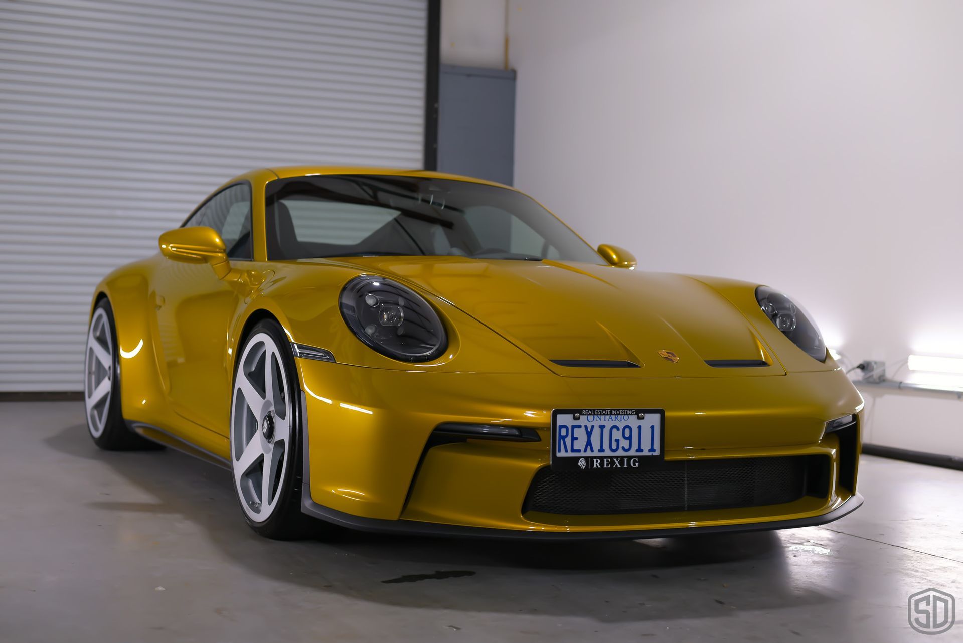 A yellow porsche 911 is parked in a garage.