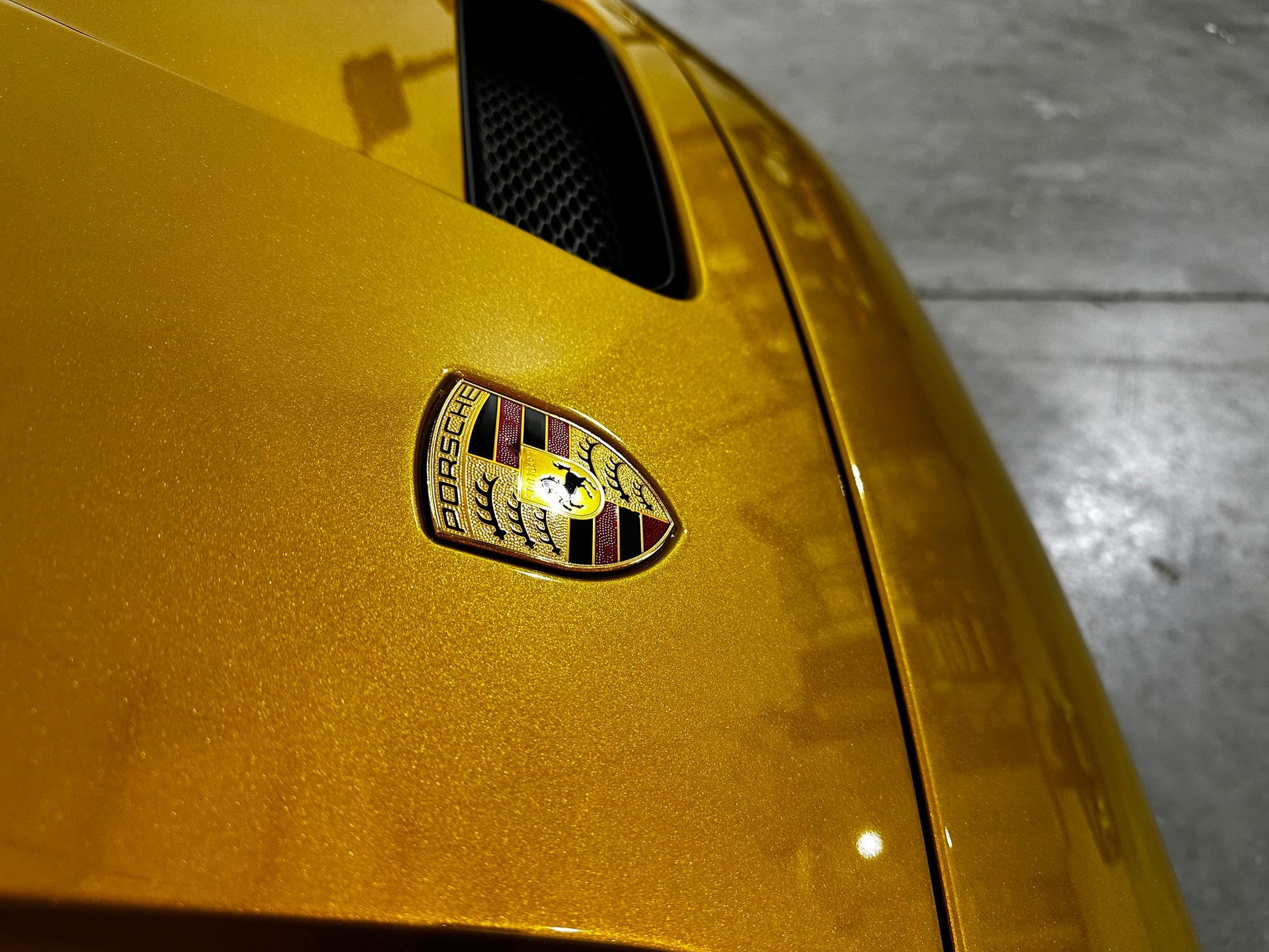 A close up of a yellow car with a porsche logo on it