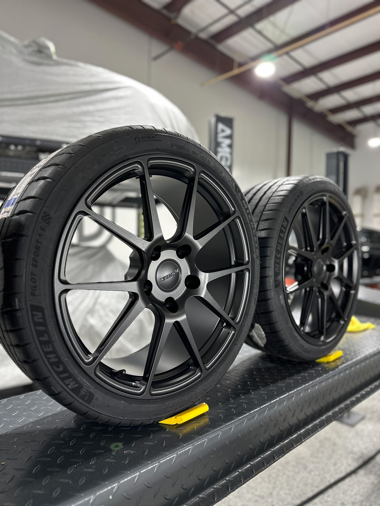 A pair of tires and wheels are sitting on a lift in a garage.
