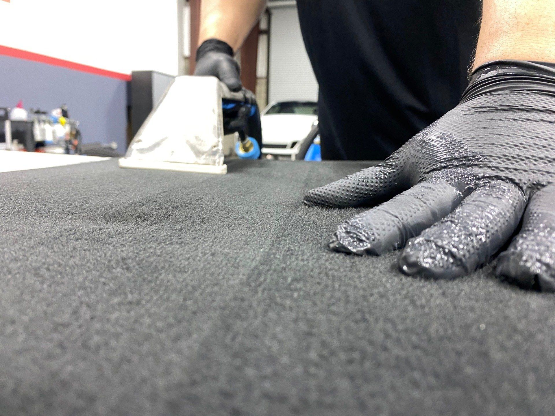 A person wearing black gloves is cleaning a black surface