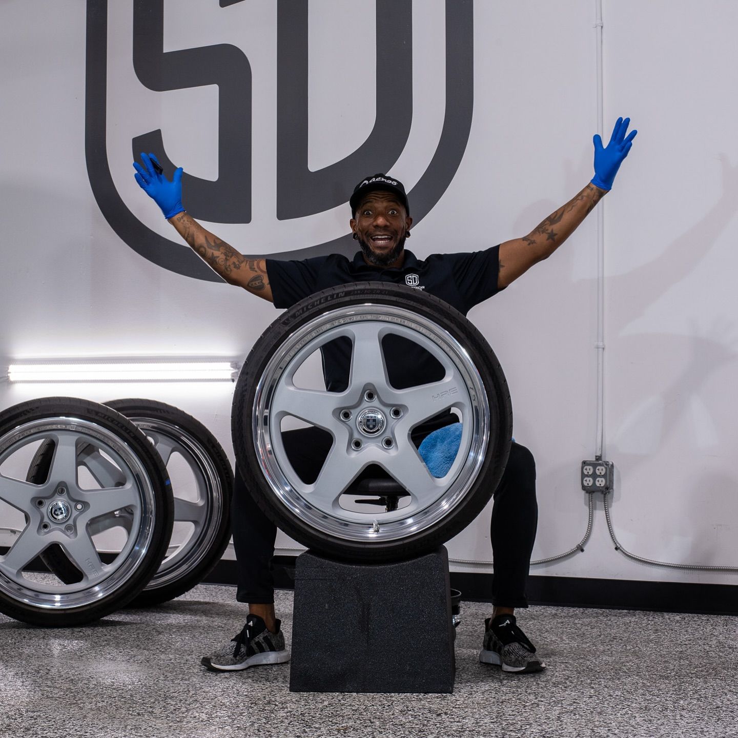 A man is sitting on a block holding a tire.