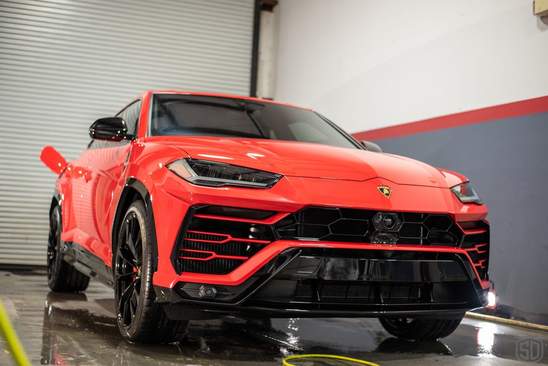 A red lamborghini urus is being washed in a garage.