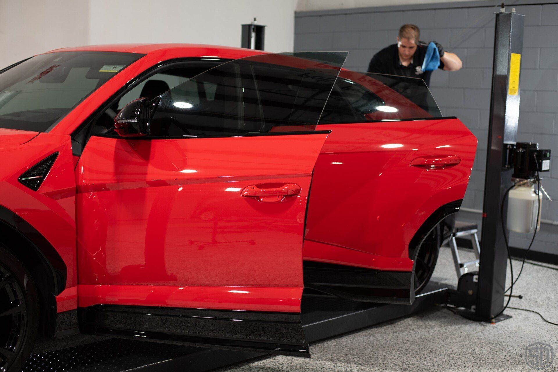 A man is cleaning a red car in a garage.
