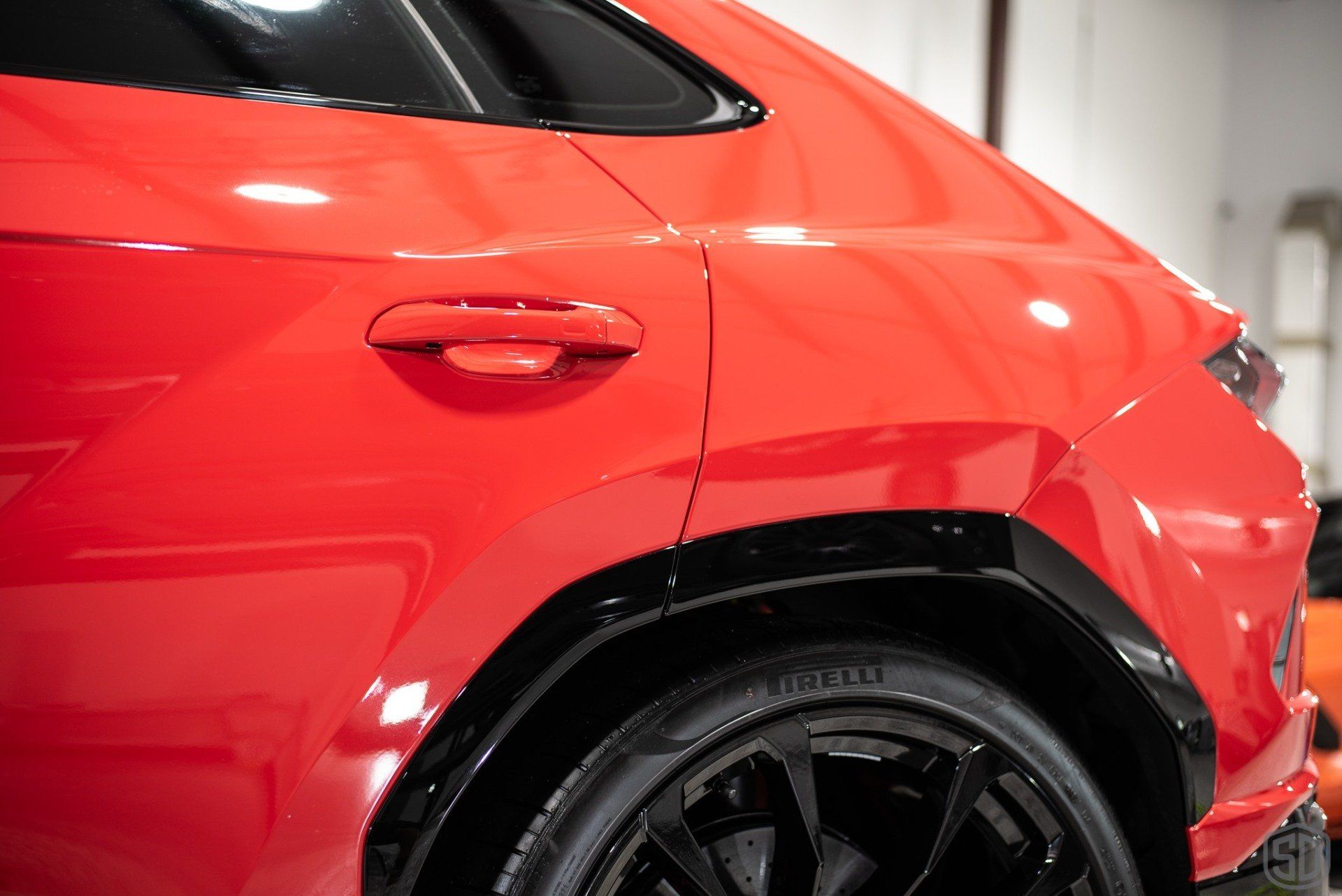 A red car is parked in a garage with a black tire.