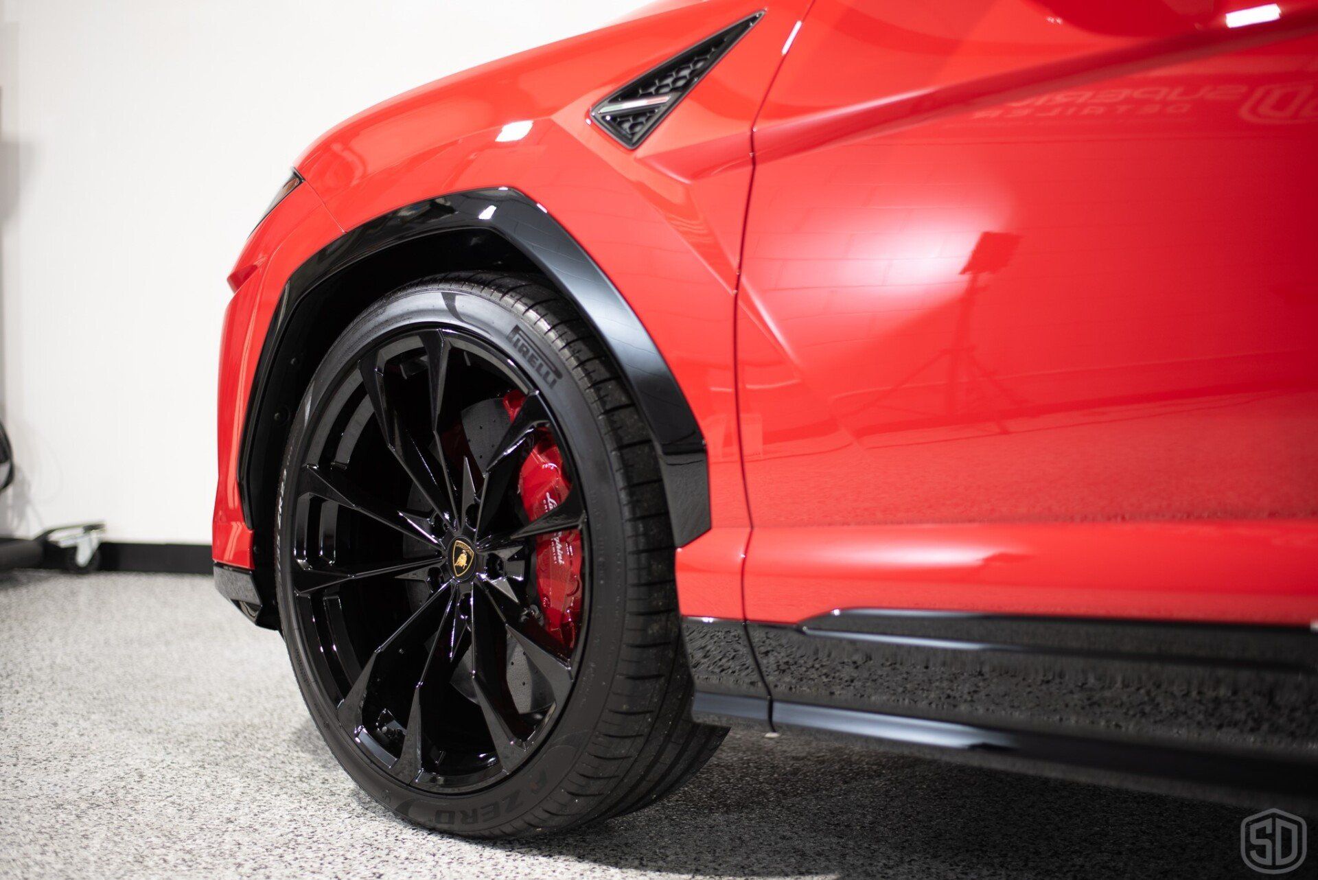 A red lamborghini urus is parked in a garage.