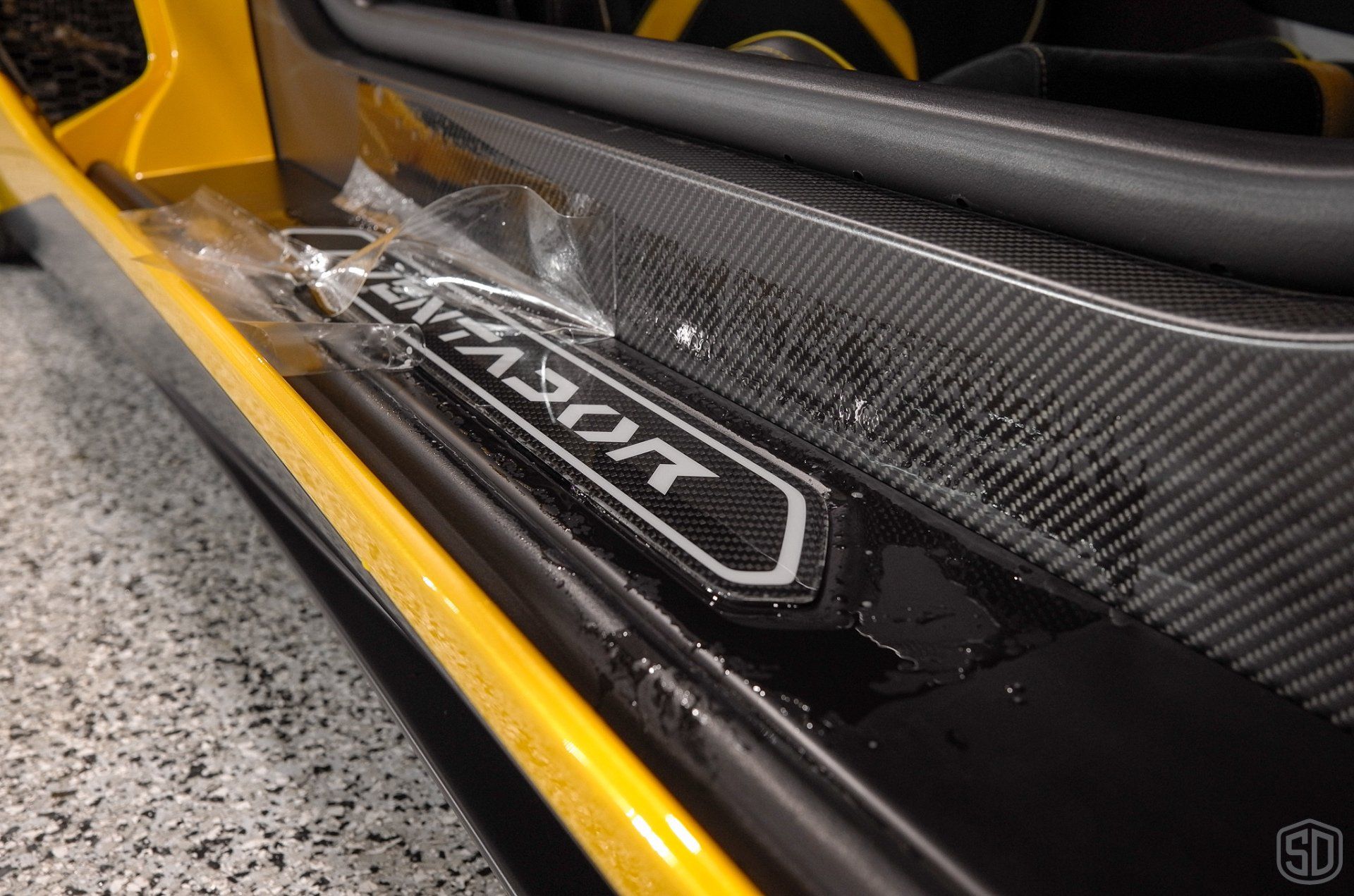 A black and yellow lamborghini aventador is parked in a garage.