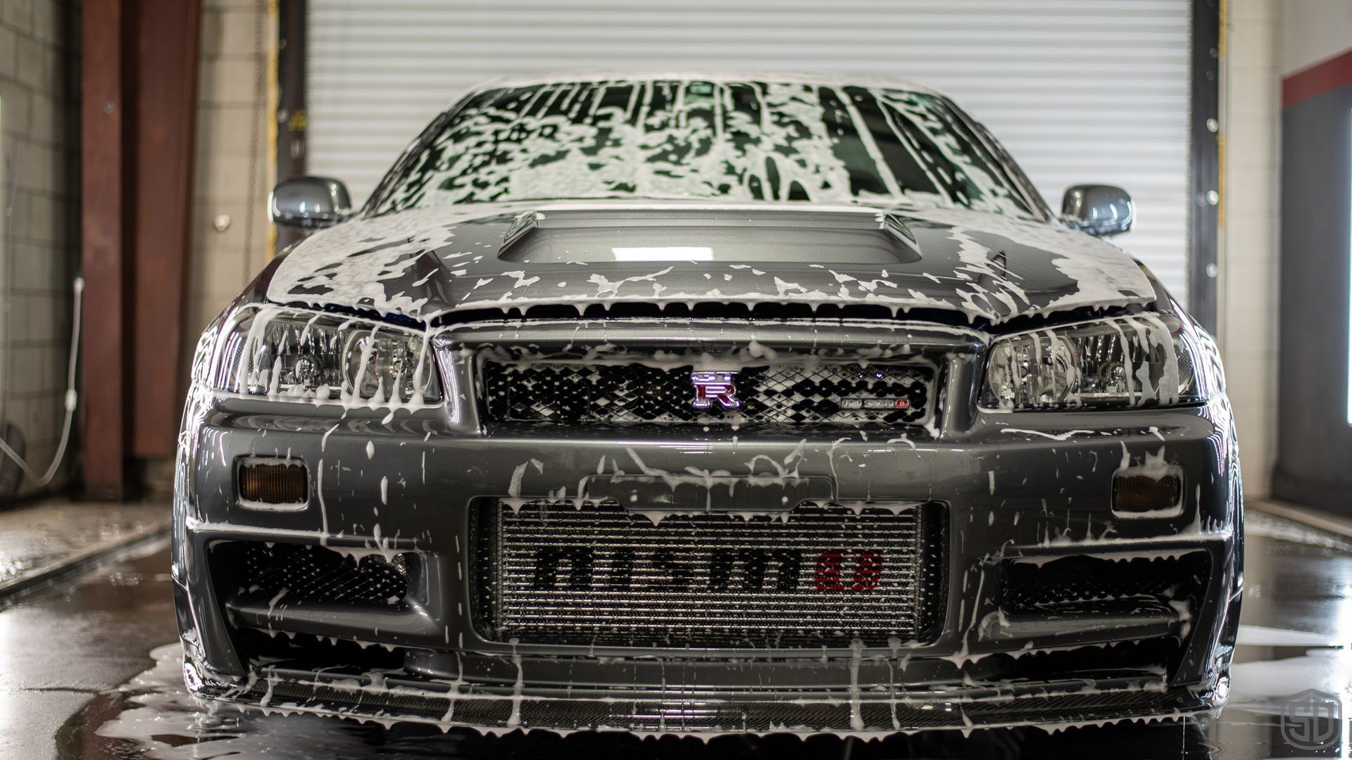 A car is covered in foam in a garage.