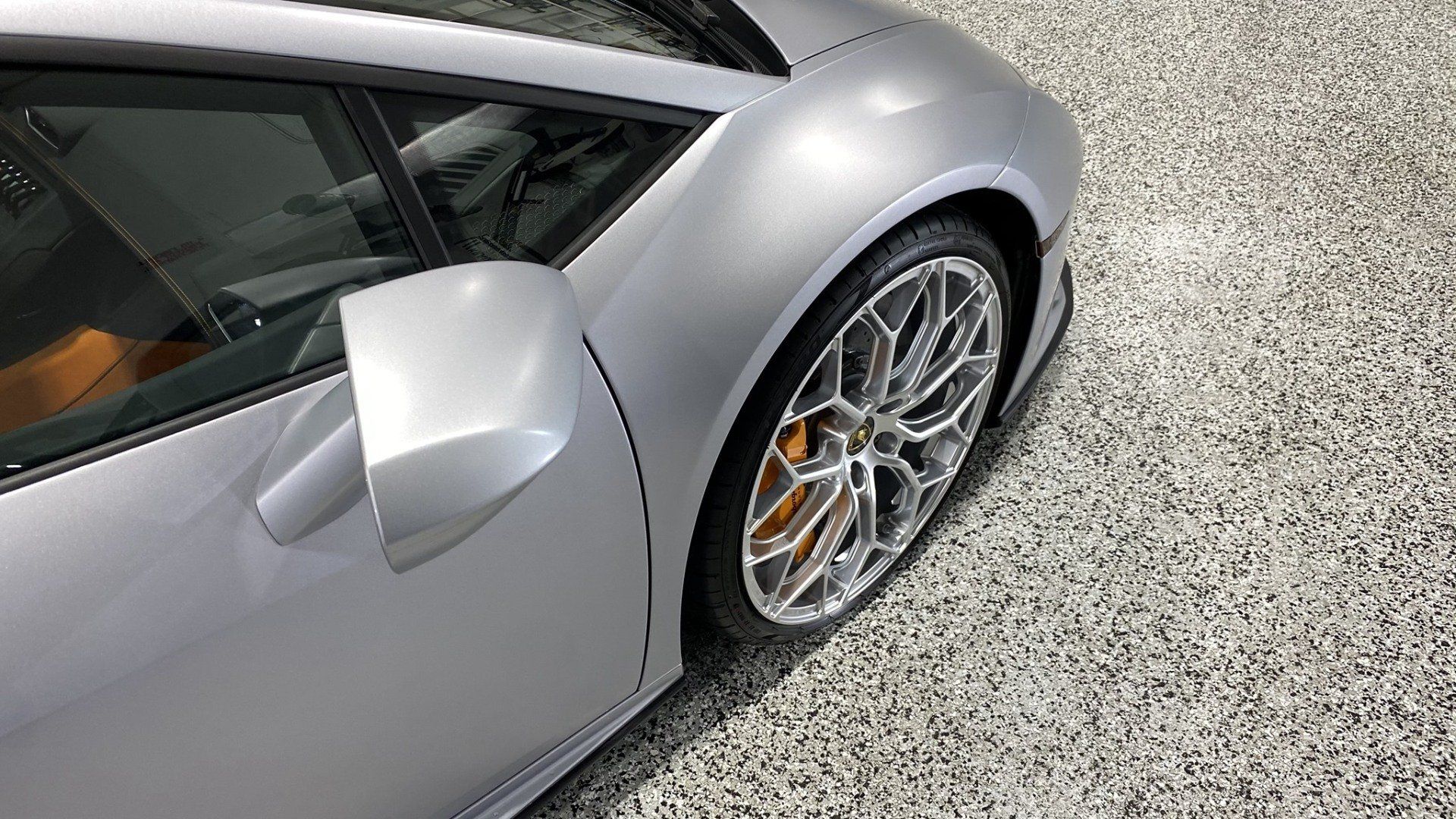 A silver sports car is parked in a garage.