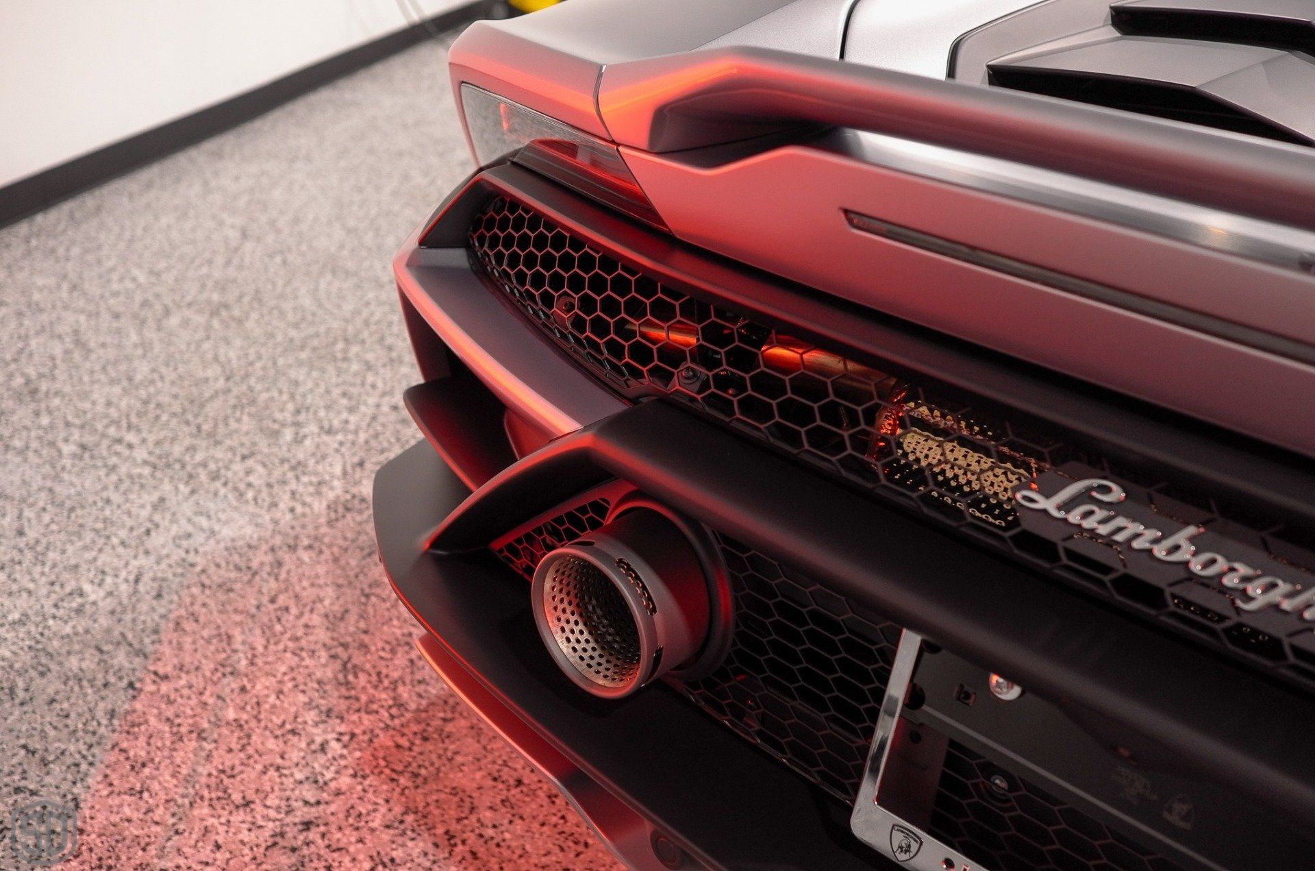 The rear end of a lamborghini huracan is shown in a garage.
