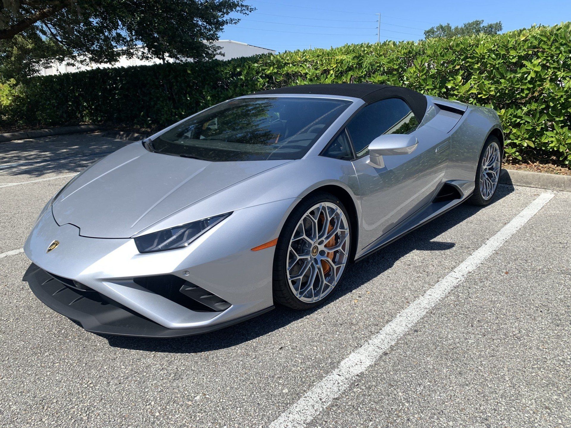 A silver lamborghini huracan convertible is parked in a parking lot.