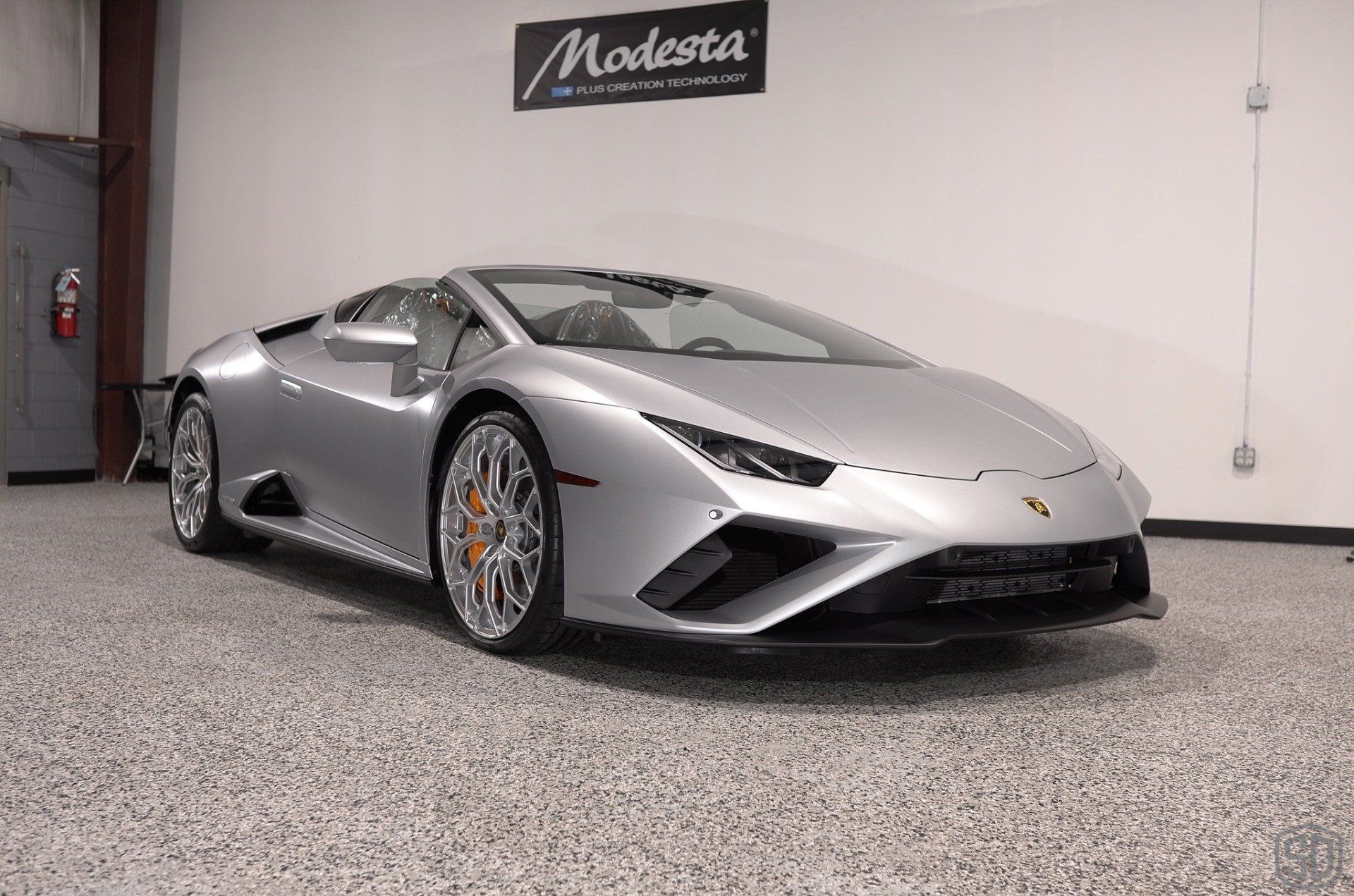 A silver lamborghini huracan is parked in a garage.
