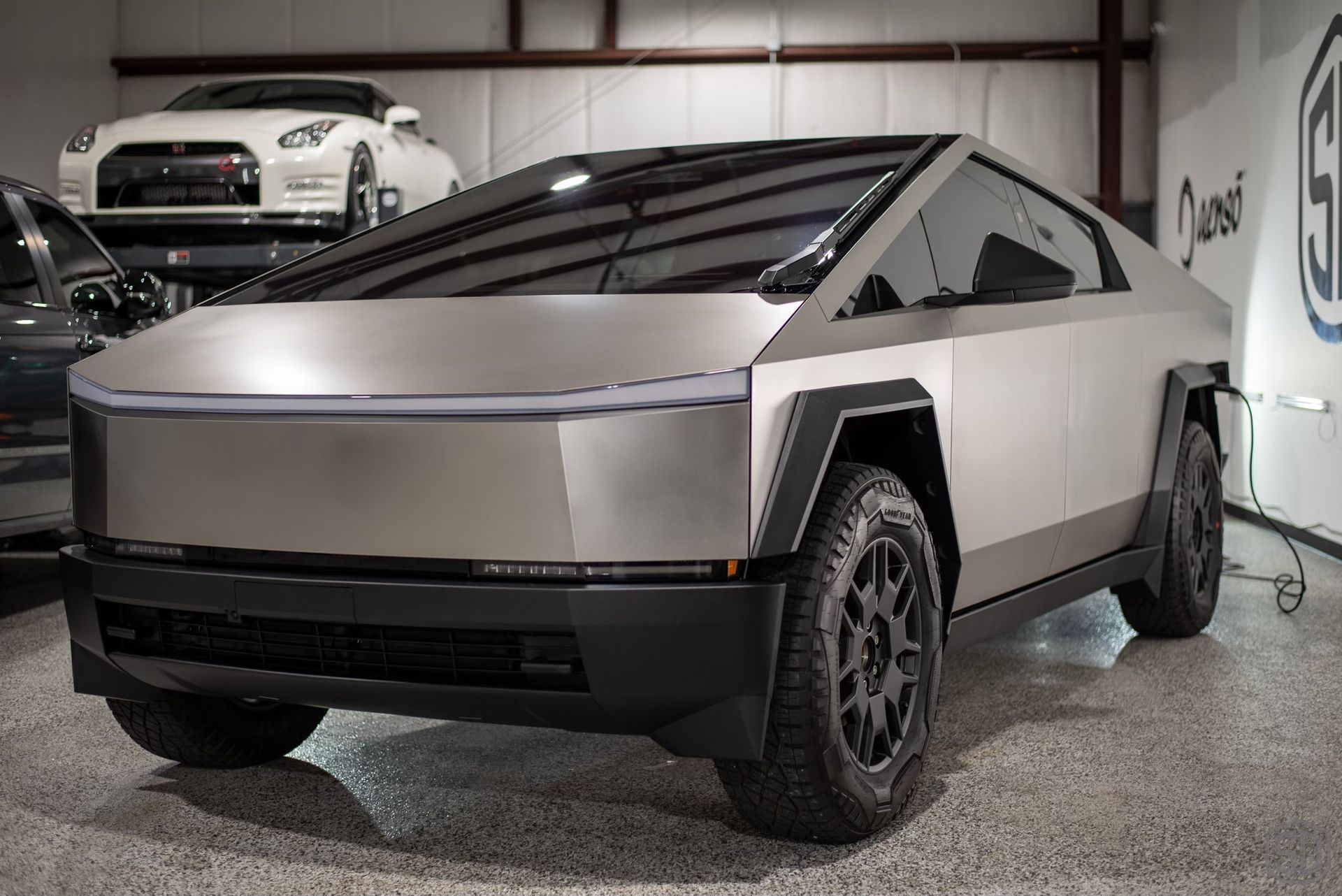 A silver tesla cybertruck is parked in a garage.