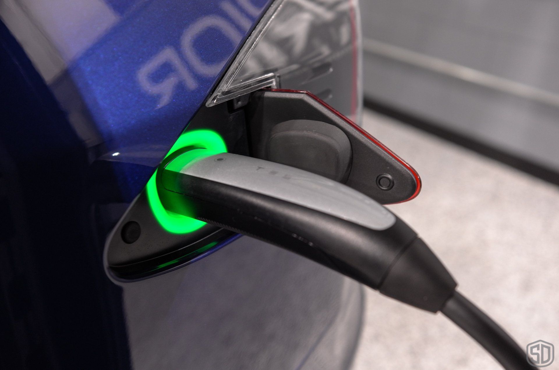 A tesla model 3 is being charged at a charging station.
