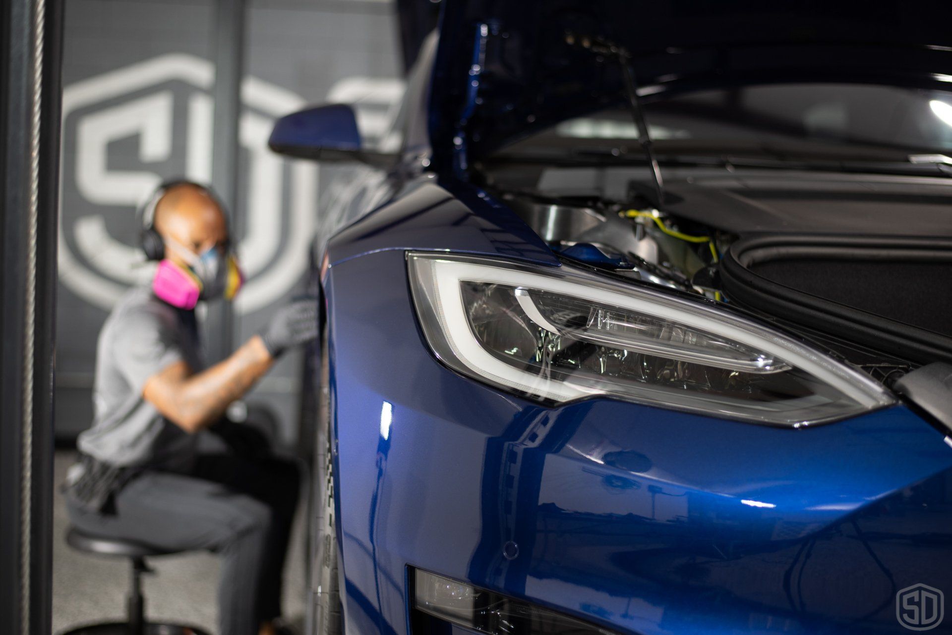 A man is working on a tesla model s in a garage.