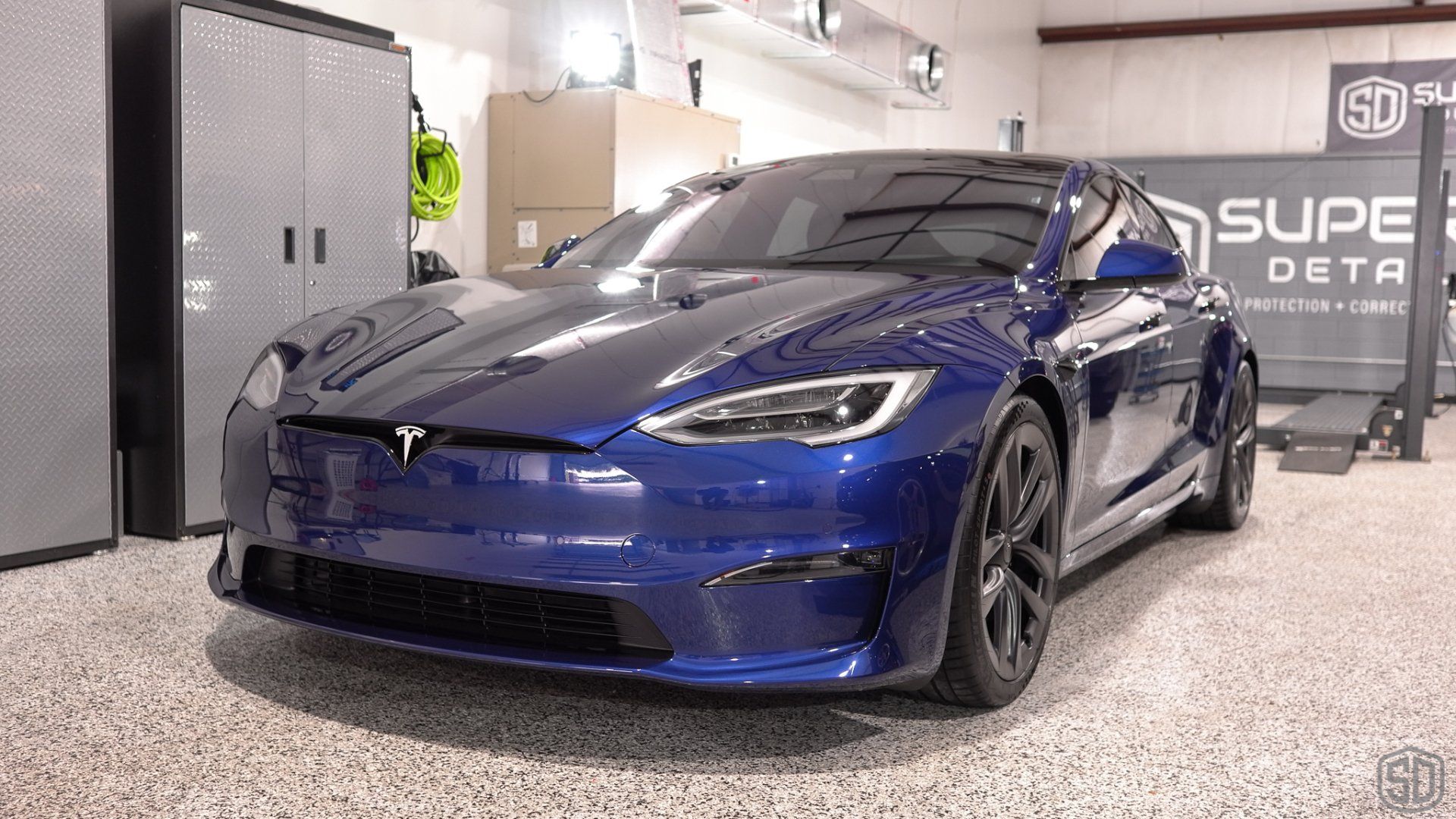 A blue tesla model s is parked in a garage.