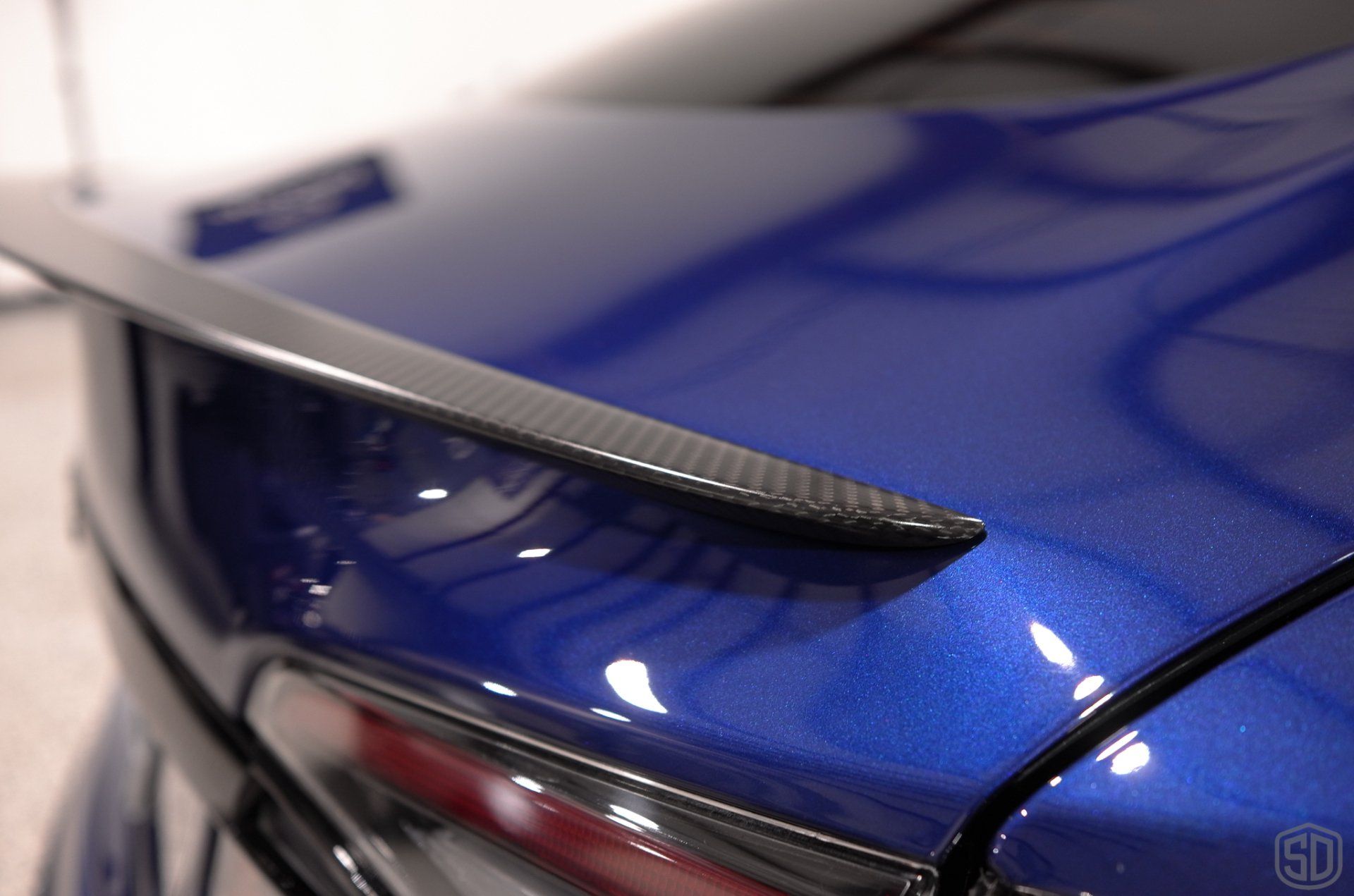 A close up of a blue car with a carbon fiber spoiler