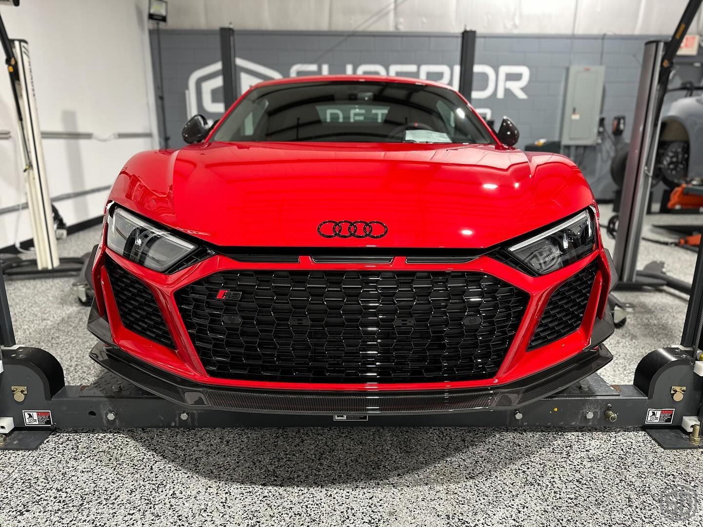 A red audi r8 is sitting on a lift in a garage.
