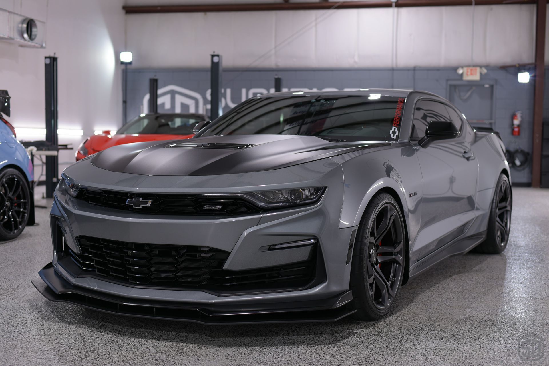 A gray chevrolet camaro is parked in a garage.