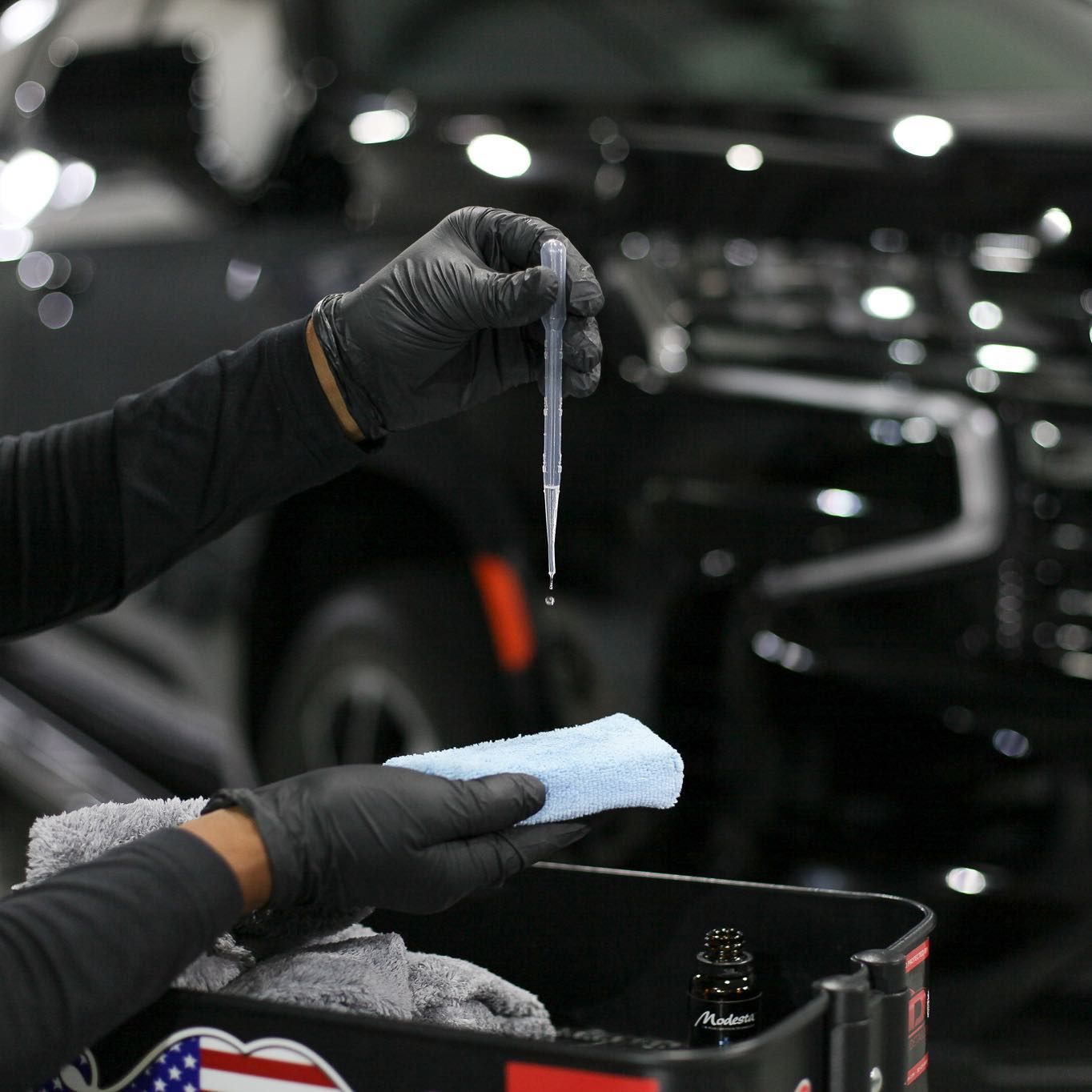 A person wearing black gloves is holding a pipette over a sponge