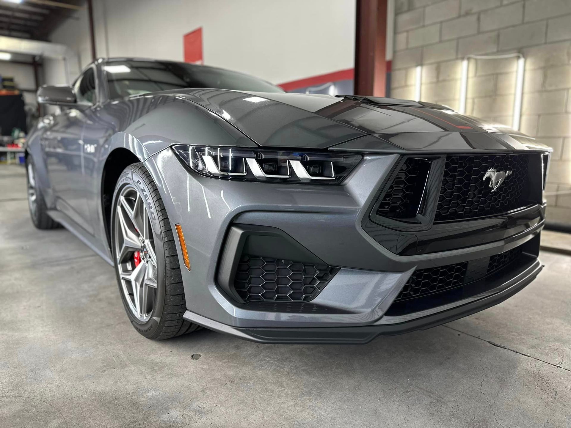 A gray ford mustang is parked in a garage.