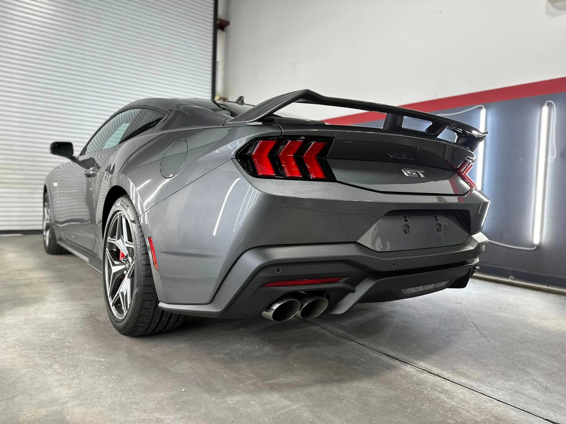 A gray ford mustang is parked in a garage.