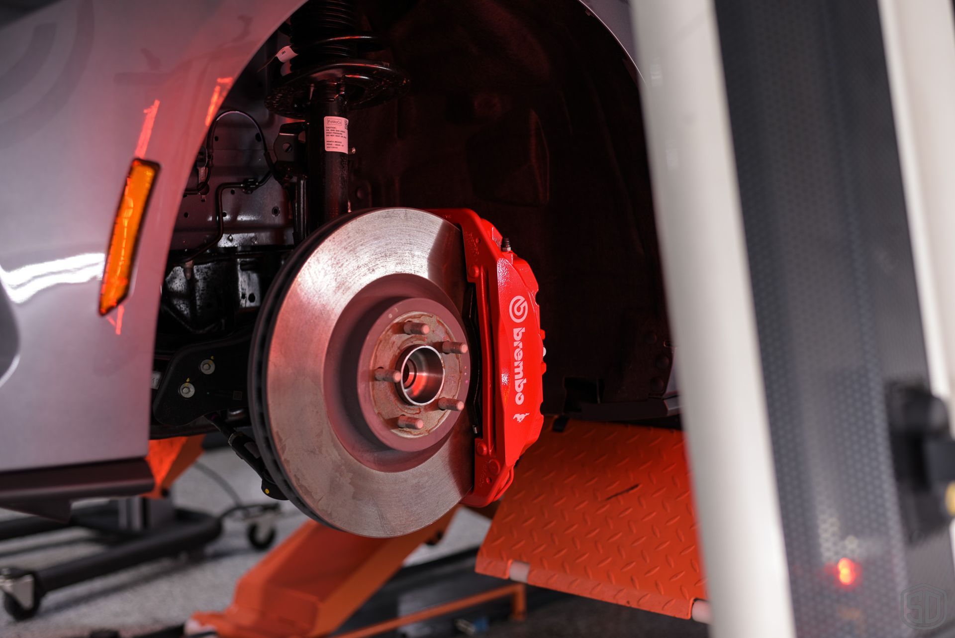 A close up of a car 's brake disc on a lift.