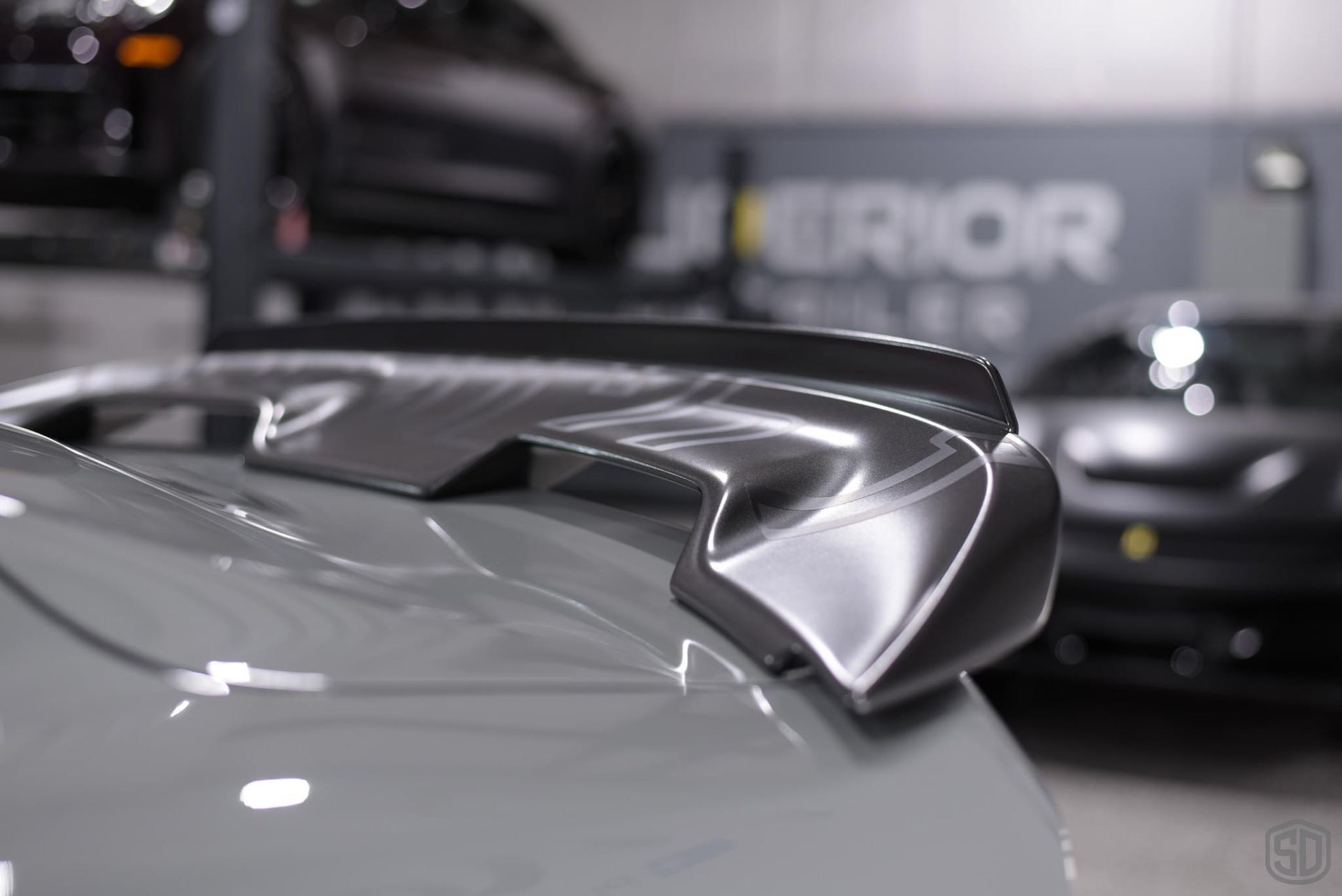 A close up of a car 's rear wing in a garage.