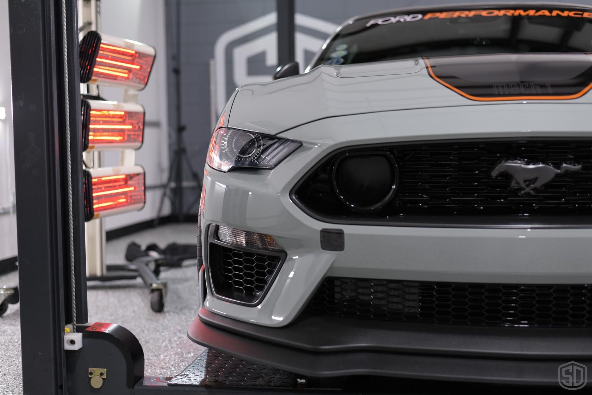 A white ford mustang is sitting on a lift in a garage.